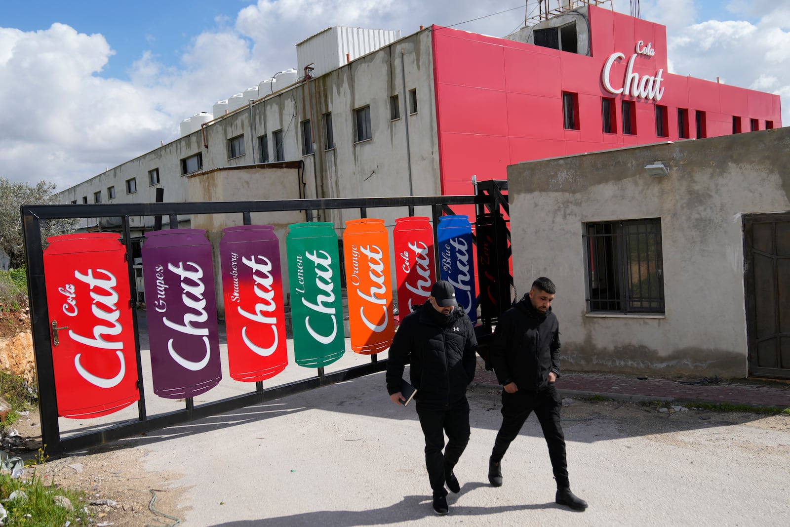 Employees walk out of the bottling plant of the Chat Cola Company in the West Bank city of Salfit, Feb. 13, 2025. (AP Photo/Nasser Nasser)