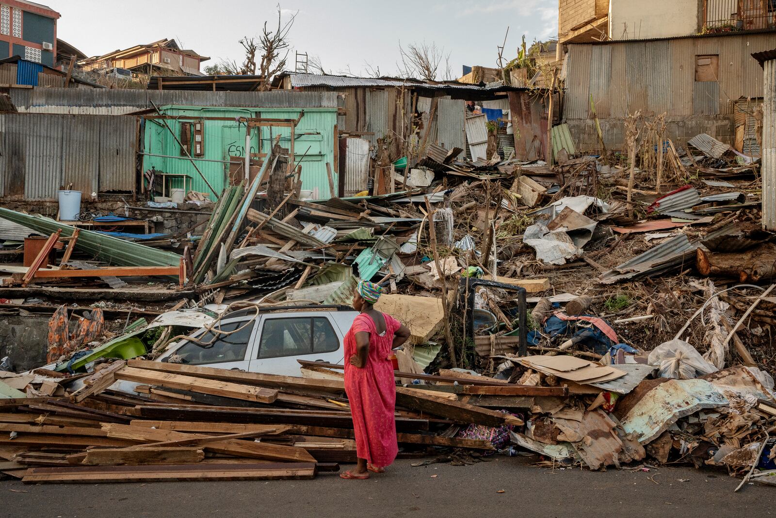 A woman looks at a destroyed home in Mamoudzou, Mayotte, Thursday, Dec. 19, 2024. (AP Photo/Adrienne Surprenant)