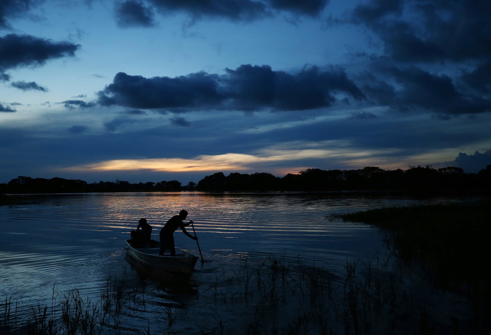 Members of the Mura Indigenous community maneuver a boat in the Lago do Soares village in Autazes, Amazonas state, Brazil, Monday, Feb. 17, 2025. (AP Photo/Edmar Barros)