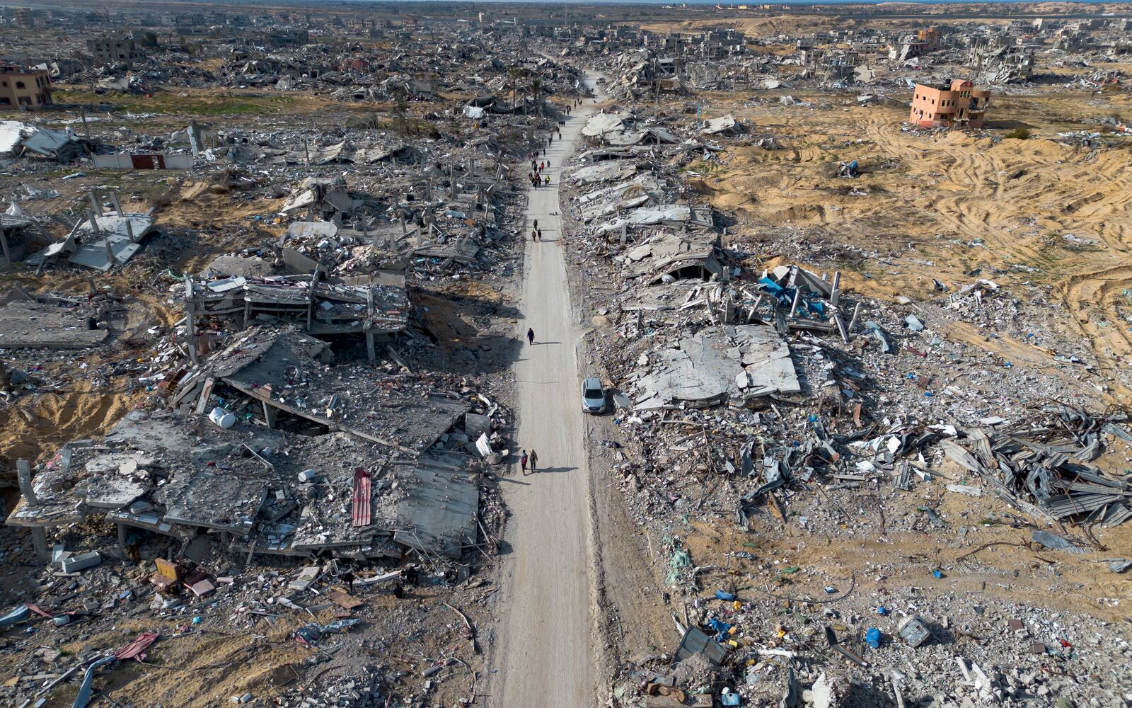 A drone photo shows Palestinians walking through the destruction left by the Israeli air and ground offensive in Rafah, following a ceasefire agreement between Hamas and Israel, Gaza Strip, Sunday, Jan. 19, 2025. (AP Photo/Jehad Alshrafi)