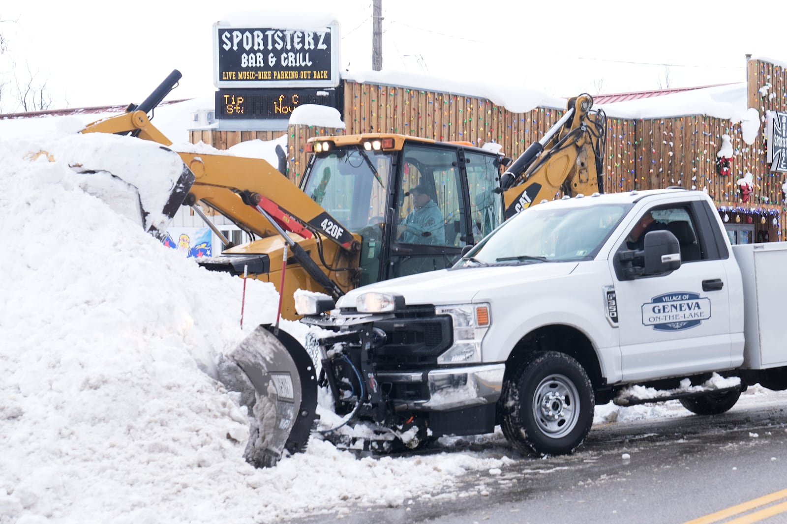 Dwayne Bennett, top, and Scott Stear, bottom, double team the snow to clear a road Monday, Dec. 2, 2024, in Geneva-on-the-Lake, Ohio. (AP Photo/Sue Ogrocki)