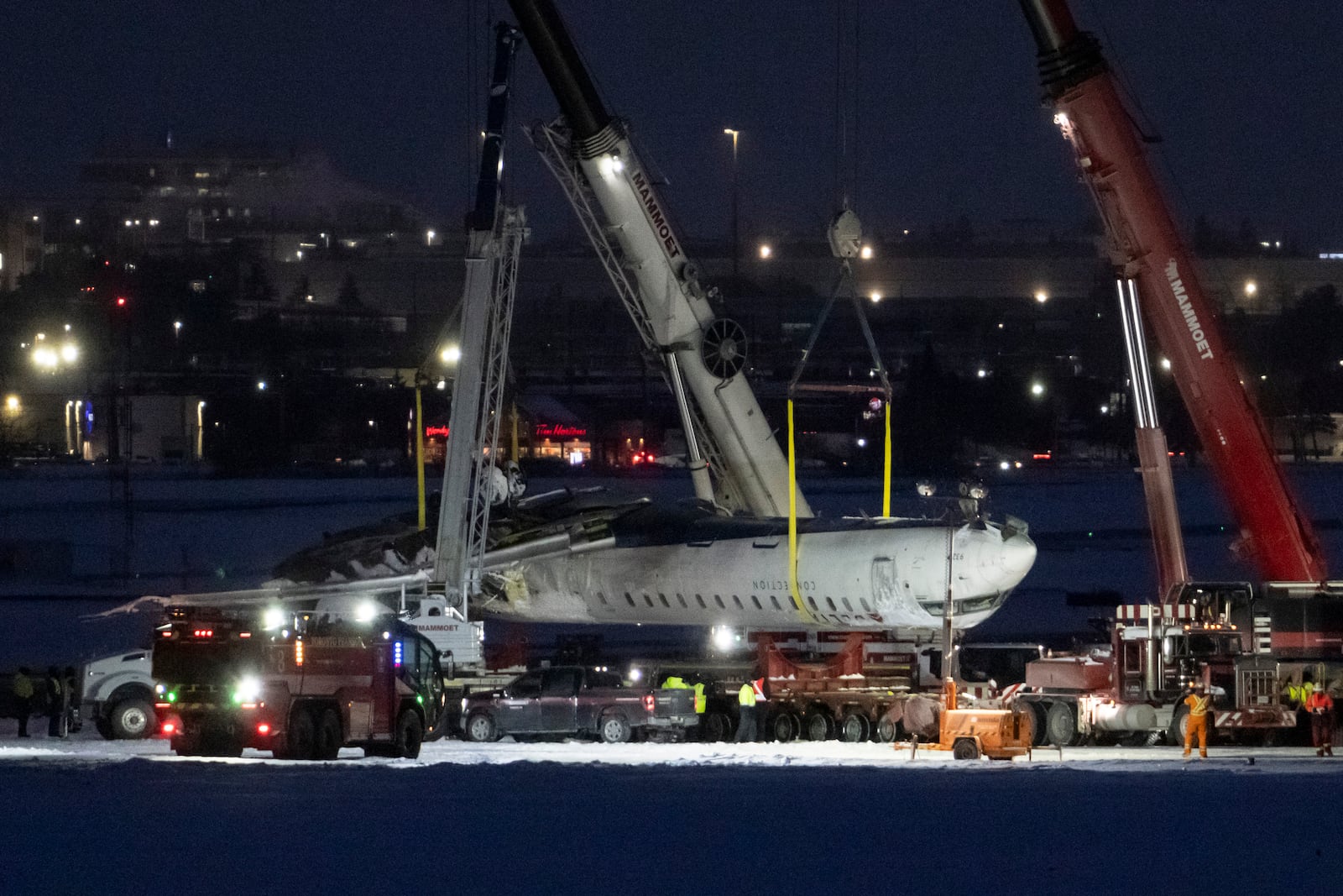 Cranes lift the wreckage of Delta flight 4819 from the runway at Toronto Pearson International Airport, in Mississauga, Ontario, Wednesday, Feb. 19, 2025. (Arlyn McAdorey/The Canadian Press via AP)