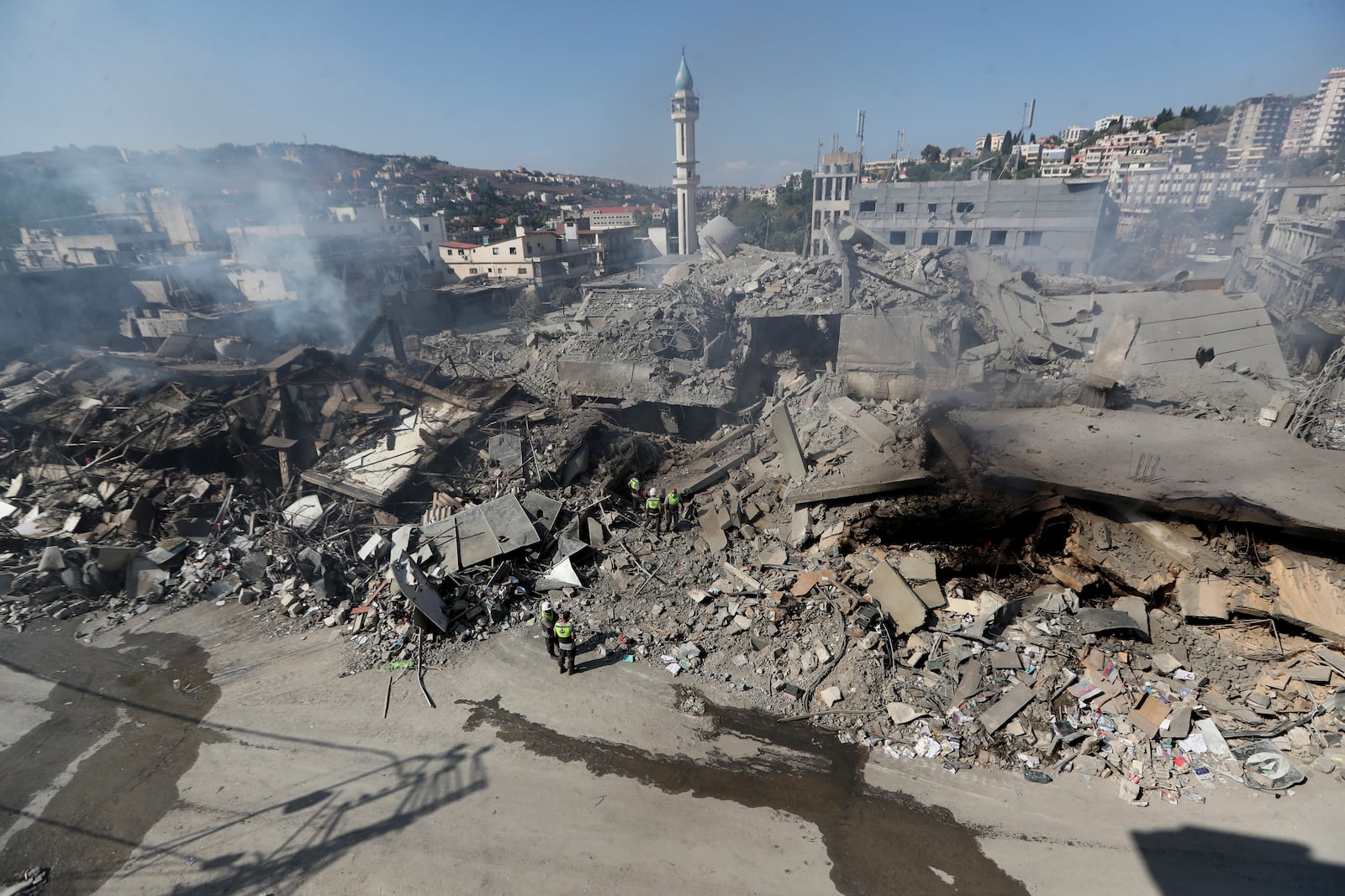 Hezbollah rescue workers search for victims amid the rubble of destroyed buildings at commercial street that was hit Saturday night by Israeli airstrikes, in Nabatiyeh town, south Lebanon, Sunday, Oct. 13, 2024. (AP Photo/Mohammed Zaatari)