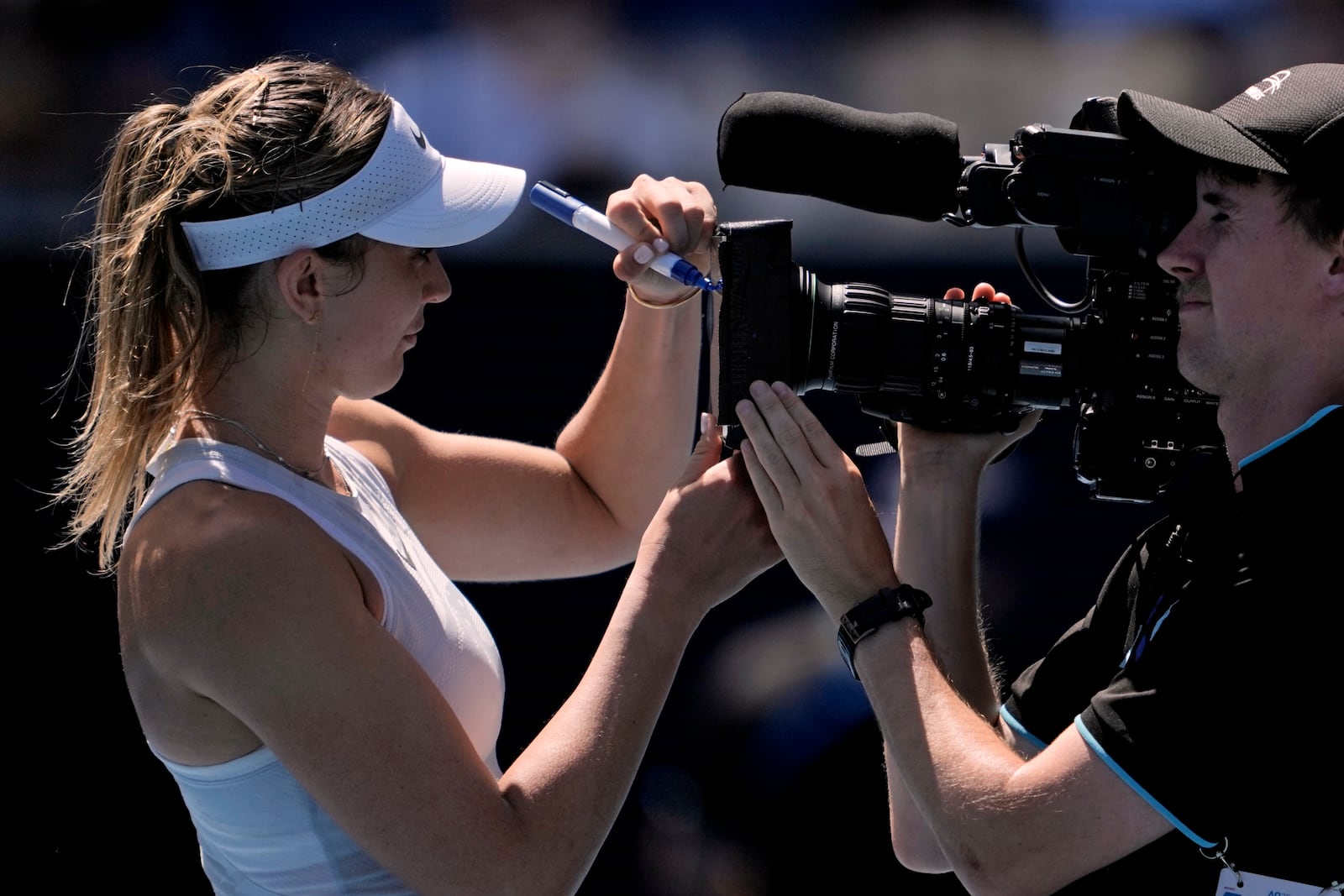 Paula Badosa of Spain autographs the screen on a television camera after defeating Marta Kostyuk of Ukraine in their third round match at the Australian Open tennis championship in Melbourne, Australia, Friday, Jan. 17, 2025. (AP Photo/Ng Han Guan)