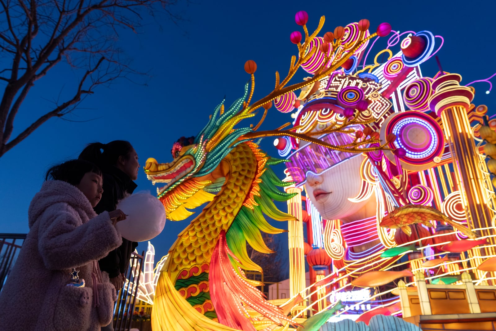 A woman and child walk past decorations at the Lantern Festival during Yuanxiao, the fifteen day of the Lunar New Year in Beijing, Wednesday, Feb. 12, 2025. (AP Photo/Ng Han Guan)