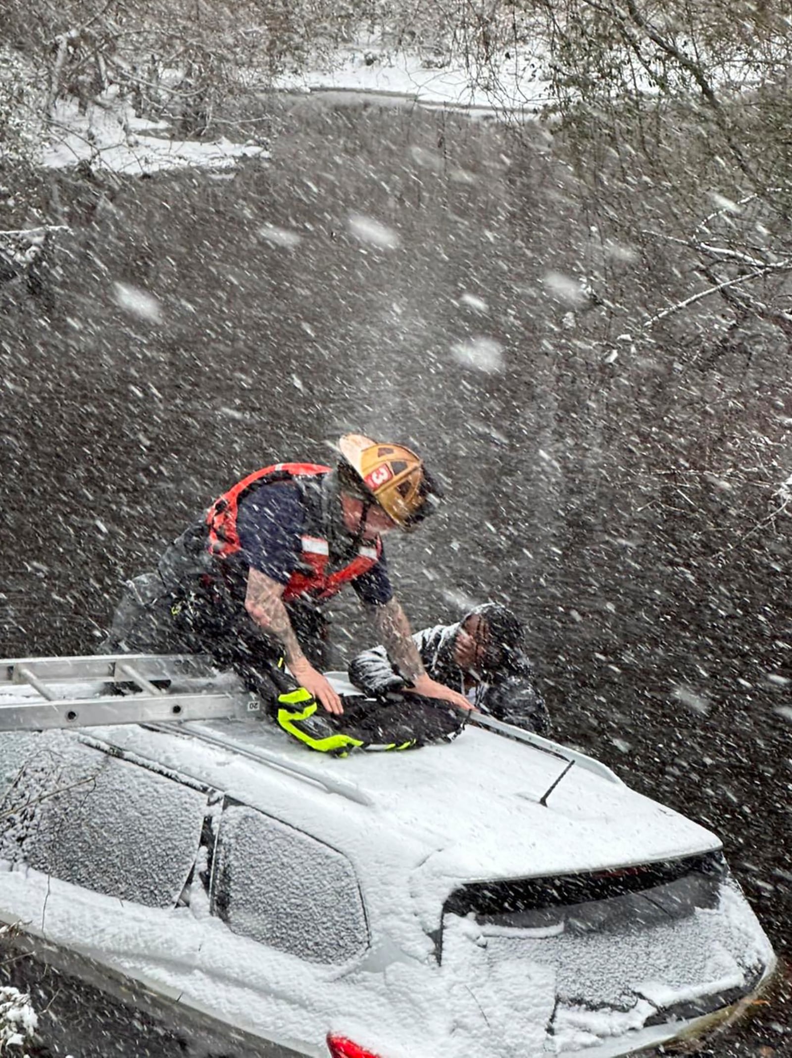 This image provided by the City of Suffolk Department of Fire & Rescue shows an emergency worker rescuing a person from an SUV that crashed into water Wednesday, Feb. 19, 2025 in Suffolk, Va. (City of Suffolk Department of Fire & Rescue via AP)