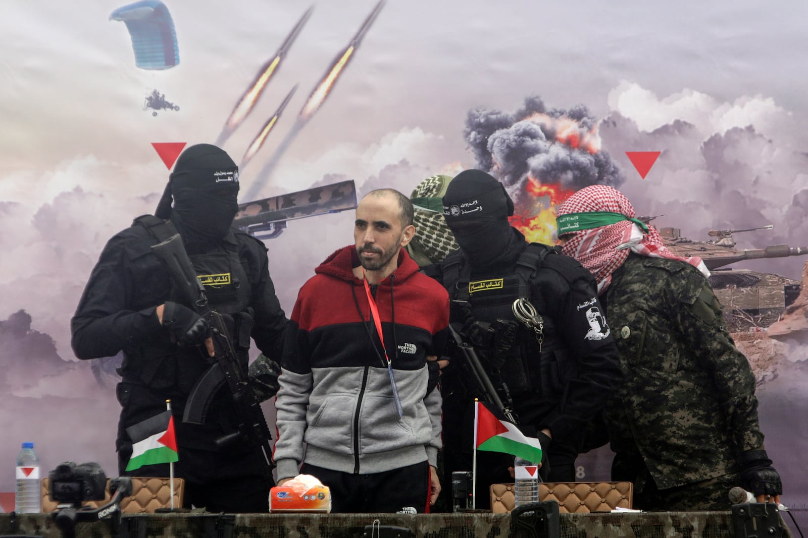 Israeli hostage Tal Shoham is escorted by Hamas fighters before being handed over to the Red Cross in Rafa, southern Gaza Strip, on Saturday, Feb. 22, 2025. (AP Photo/Jehad Alshrafi)