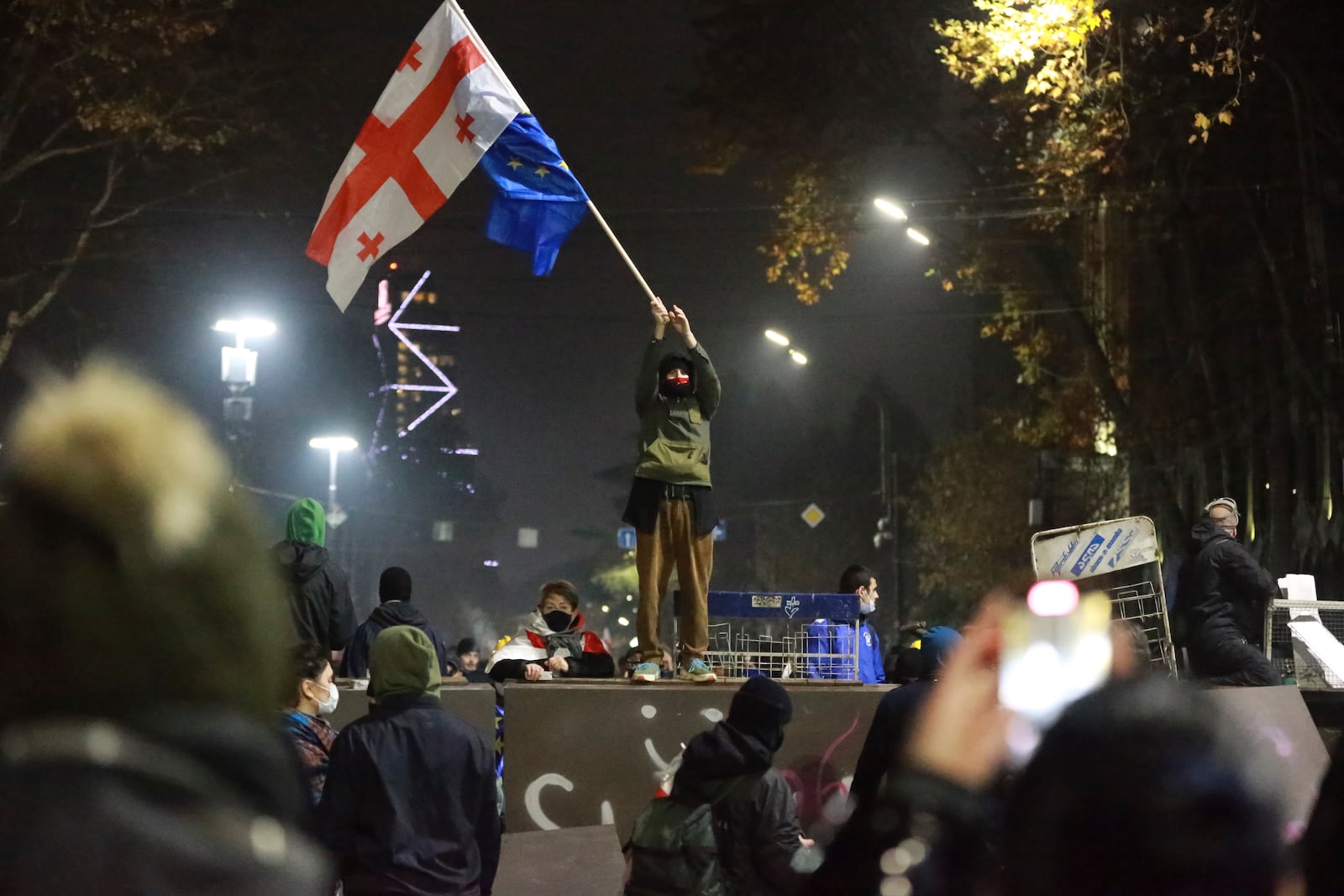 A demonstrator stands with Georgian national and EU flags during a rally outside the parliament's building to protest the government's decision to suspend negotiations on joining the European Union for four years in Tbilisi, Georgia, on early Sunday, Dec. 1, 2024. (AP Photo/Zurab Tsertsvadze)