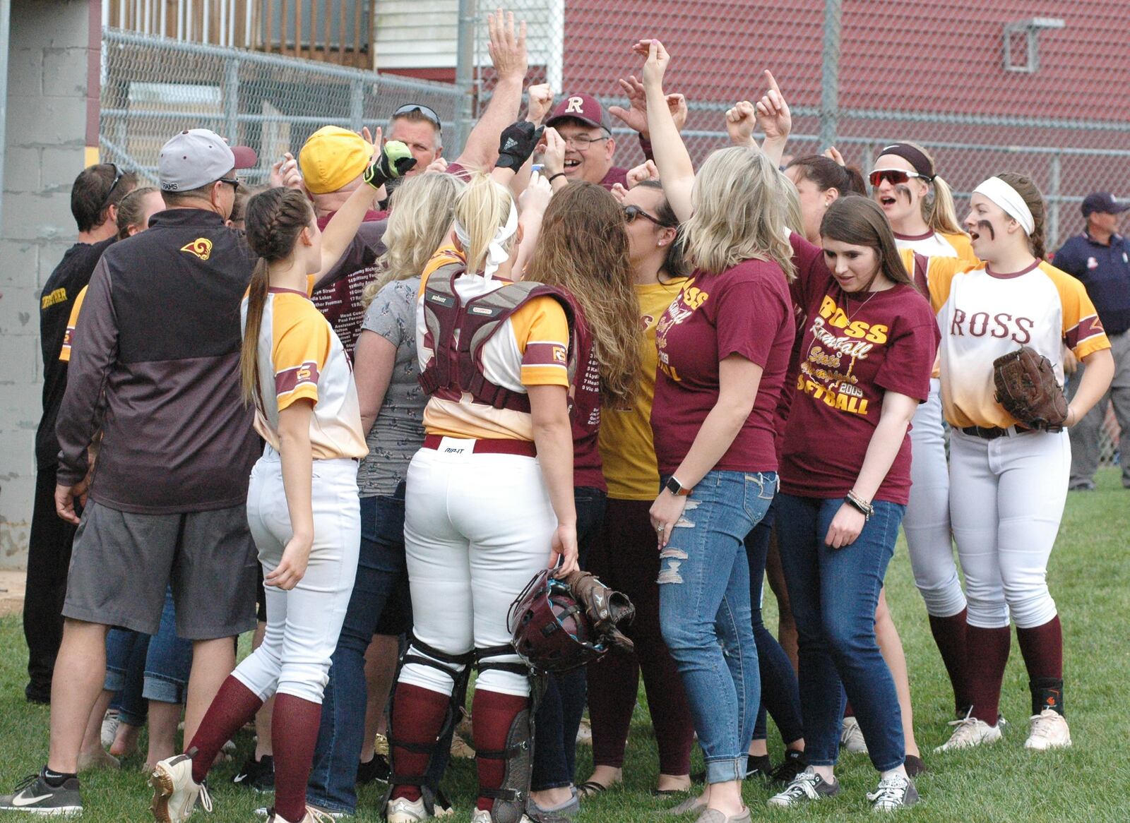 Members of the Ross High School 2009 Division II state championship softball team huddle with players from the 2019 squad before Wednesday’s 12-2 victory over visiting Northwest. RICK CASSANO/STAFF