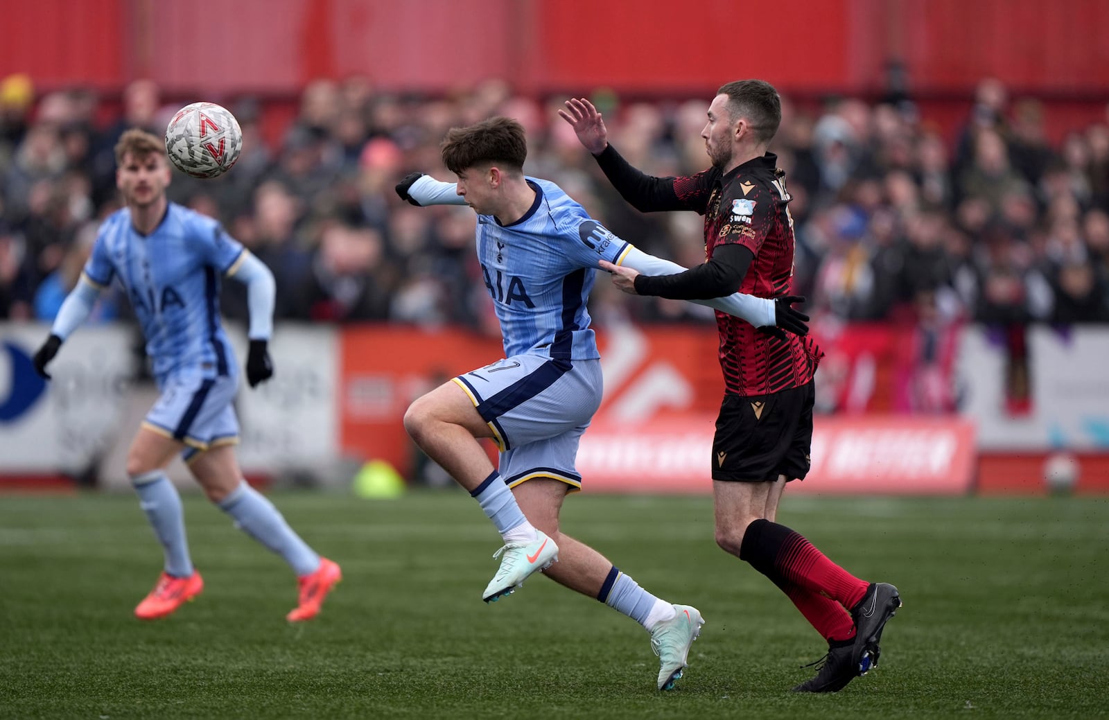 Tottenham Hotspur's Mikey Moore, left, and Tamworth's Thomas McLinchey battle for the ball during the English FA Cup third round match at The Lamb Ground, Tamworth, England, Sunday Jan. 12, 2025. (Joe Giddens/PA via AP)