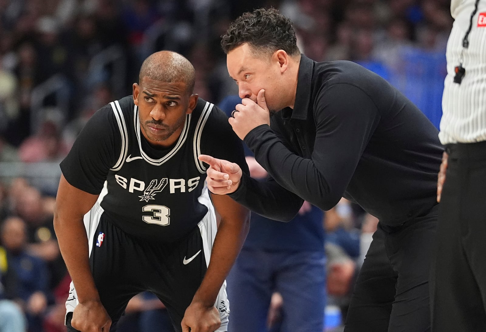 San Antonio Spurs interim head coach Mitch Johnson, right, confers with guard Chris Paul (3) in the second half of an NBA basketball game against the Denver Nuggets Friday, Jan. 3, 2025, in Denver. (AP Photo/David Zalubowski)