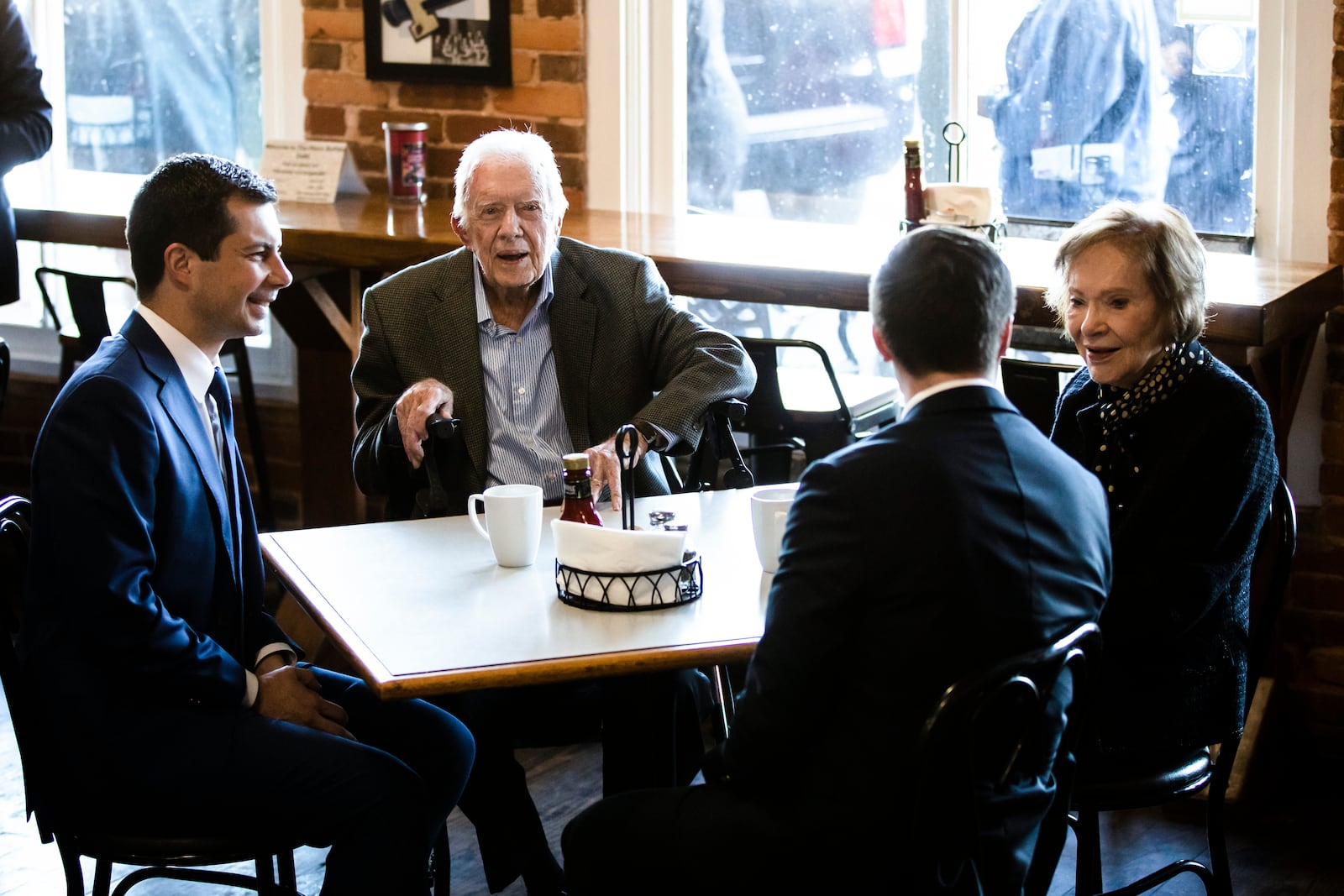 FILE - Democratic presidential candidate and former South Bend, Ind., mayor, Pete Buttigieg, left, and his husband Chasten Buttigieg, second from the right, meet with former President Jimmy Carter and former first lady Rosalynn Carter at the Buffalo Cafe in Plains, Ga., March 1, 2020. (AP Photo/Matt Rourke, File)