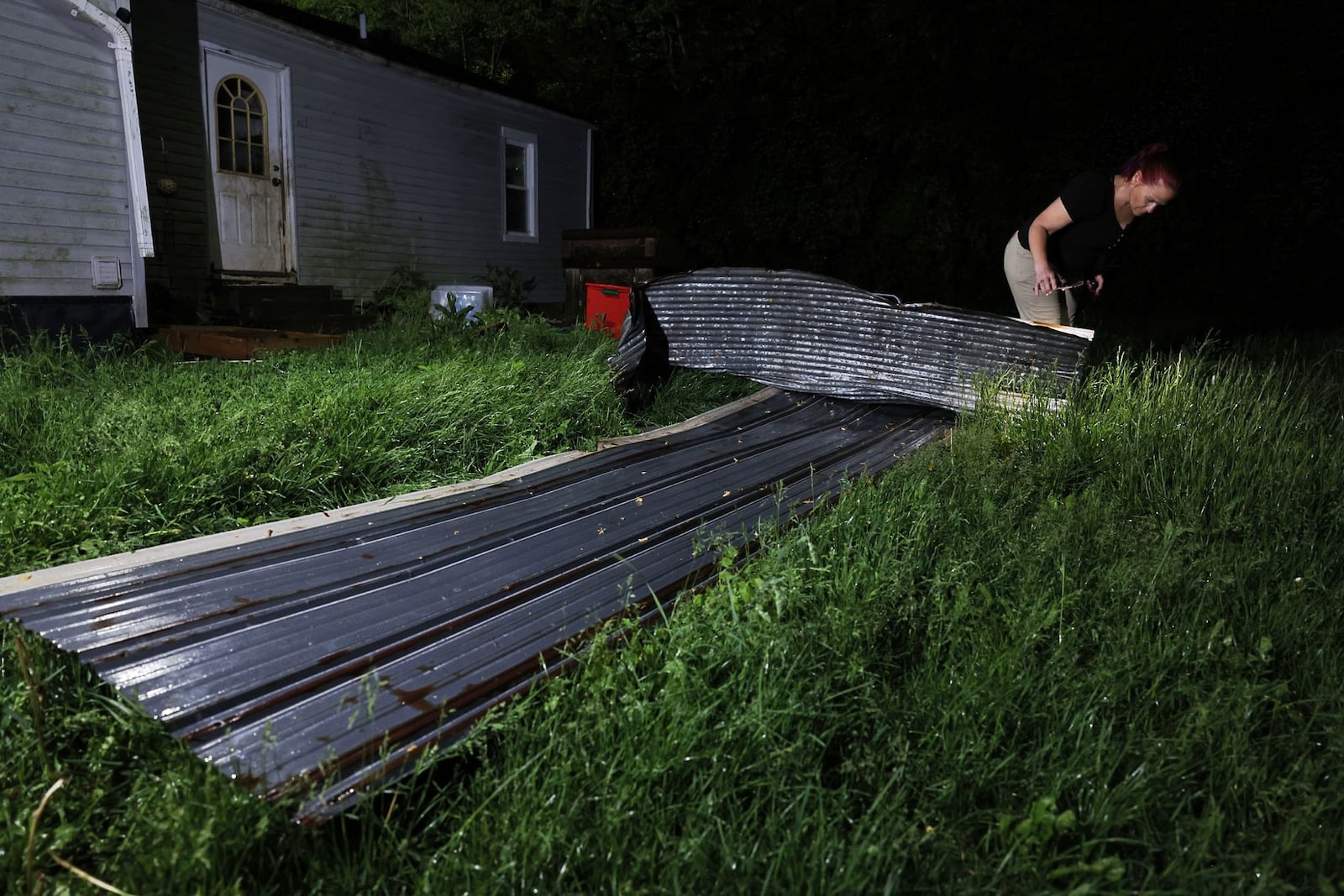 Holly Mullen investigates a piece of metal found in her back yard on Stillwell Beckett Road in Hanover Twp. 
A silo was blown into the middle if the road just up the street from her house. | NICK GRAHAM, STAFF