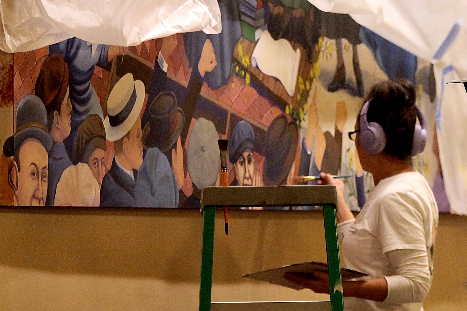 Artist Phyllis Garibay-Coon, of Manhattan, Kansas, touches up her mural honoring Kansas women who campaigned for decades for voting rights, two days before its official unveiling at the Statehouse, Monday, Jan. 27, 2025, in Topeka, Kan. (AP Photo/John Hanna)