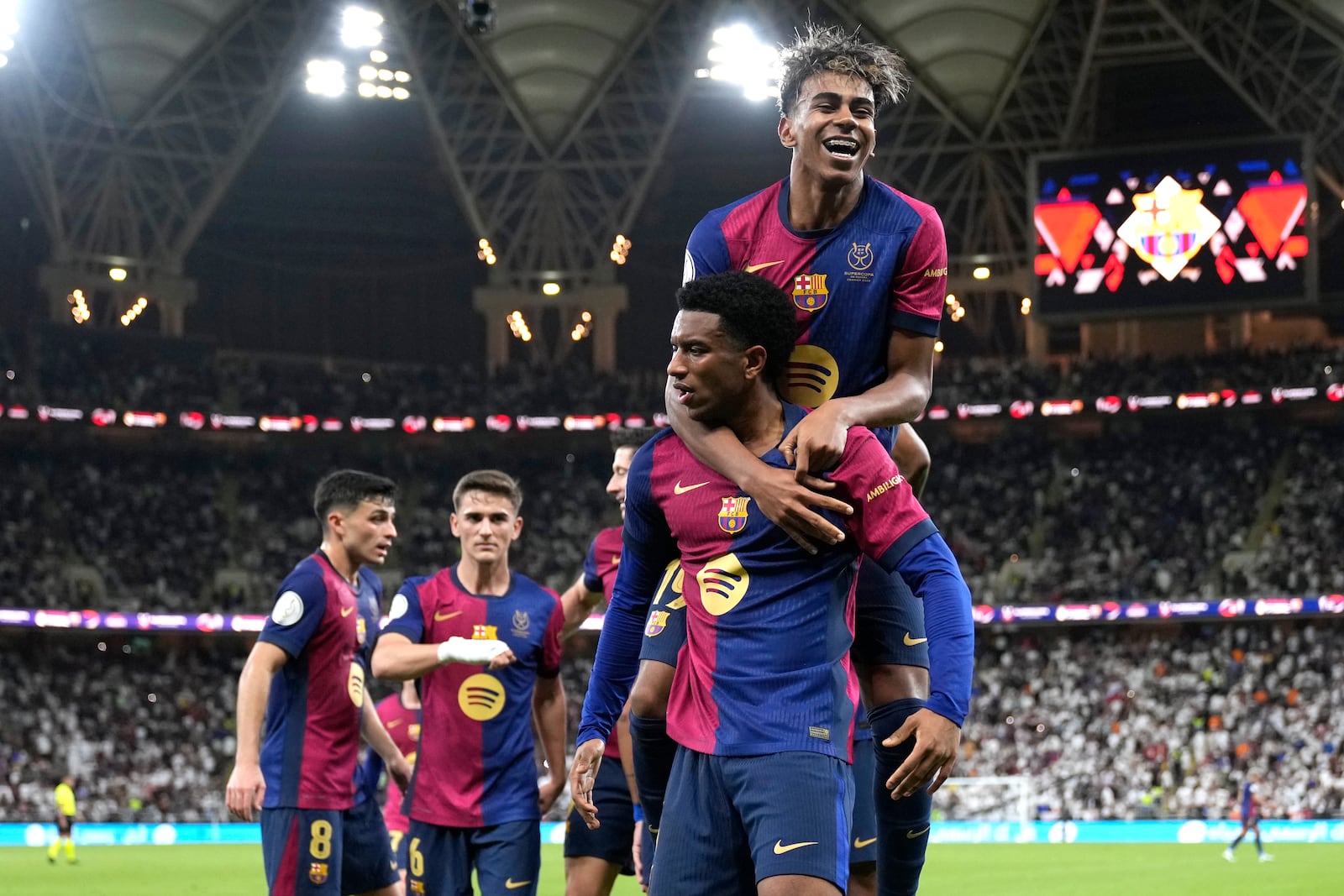 Barcelona's Alejandro Balde and Barcelona's Lamine Yamal, top, react during the Spain Super Cup final soccer match between Real Madrid and Barcelona at King Abdullah Stadium in Jeddah, Saudi Arabia, Sunday, Jan. 12, 2025. (AP Photo/Altaf Qadri)