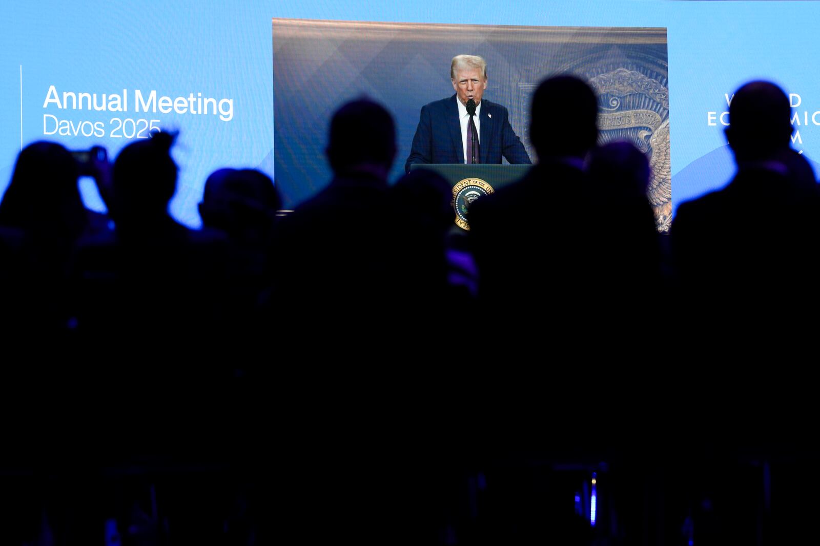 Attendees listen to a virtual speech delivered by U.S. president Donald Trump, at the Annual Meeting of World Economic Forum in Davos, Switzerland, Thursday, Jan. 23, 2025. (AP Photo/Markus Schreiber)