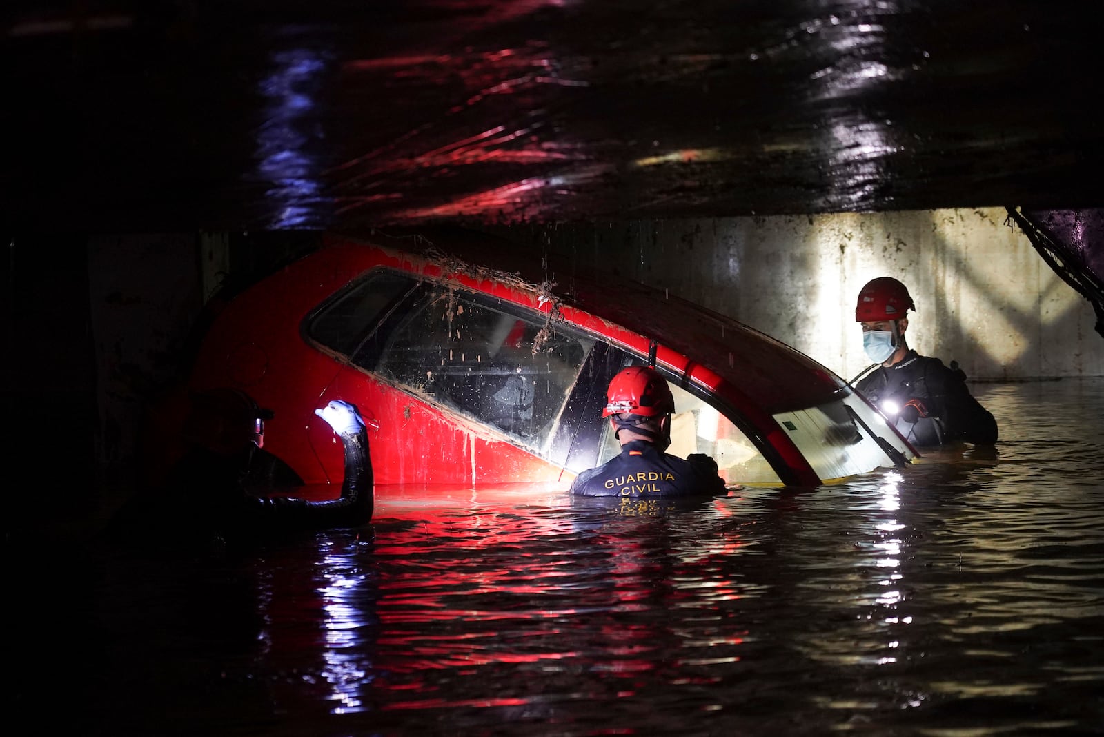 Civil Guards walk in a flooded indoor car park to check cars for bodies after floods in Paiporta, near Valencia, Spain, Monday, Nov. 4, 2024. (AP Photo/Alberto Saiz)