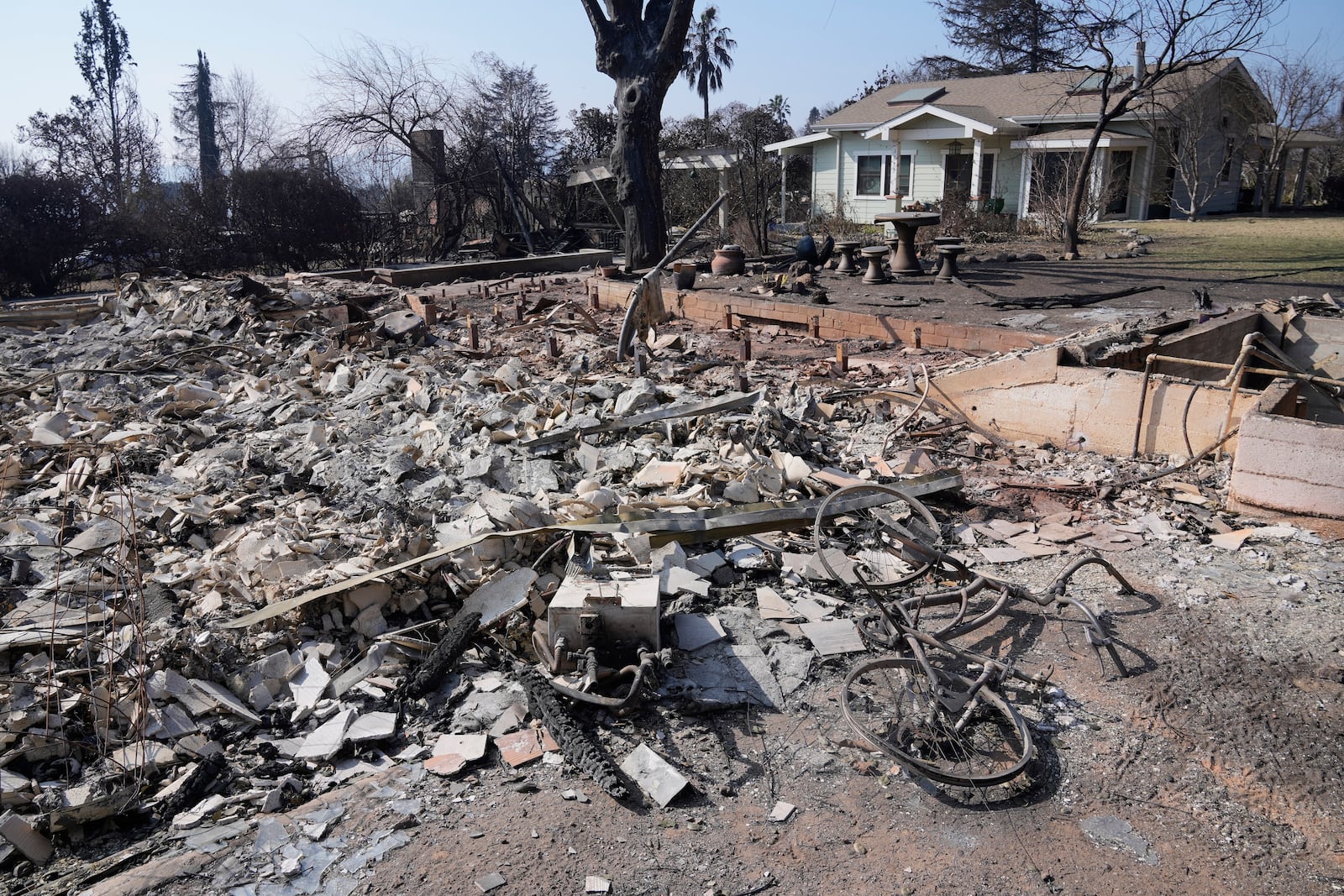 Debris from a destroyed home is seen as a newly built ADU (accessory dwelling unit) stands behind after surviving the Eaton Fire, Sunday, Jan. 19, 2025, in Altadena, Calif. (AP Photo/Damian Dovarganes)