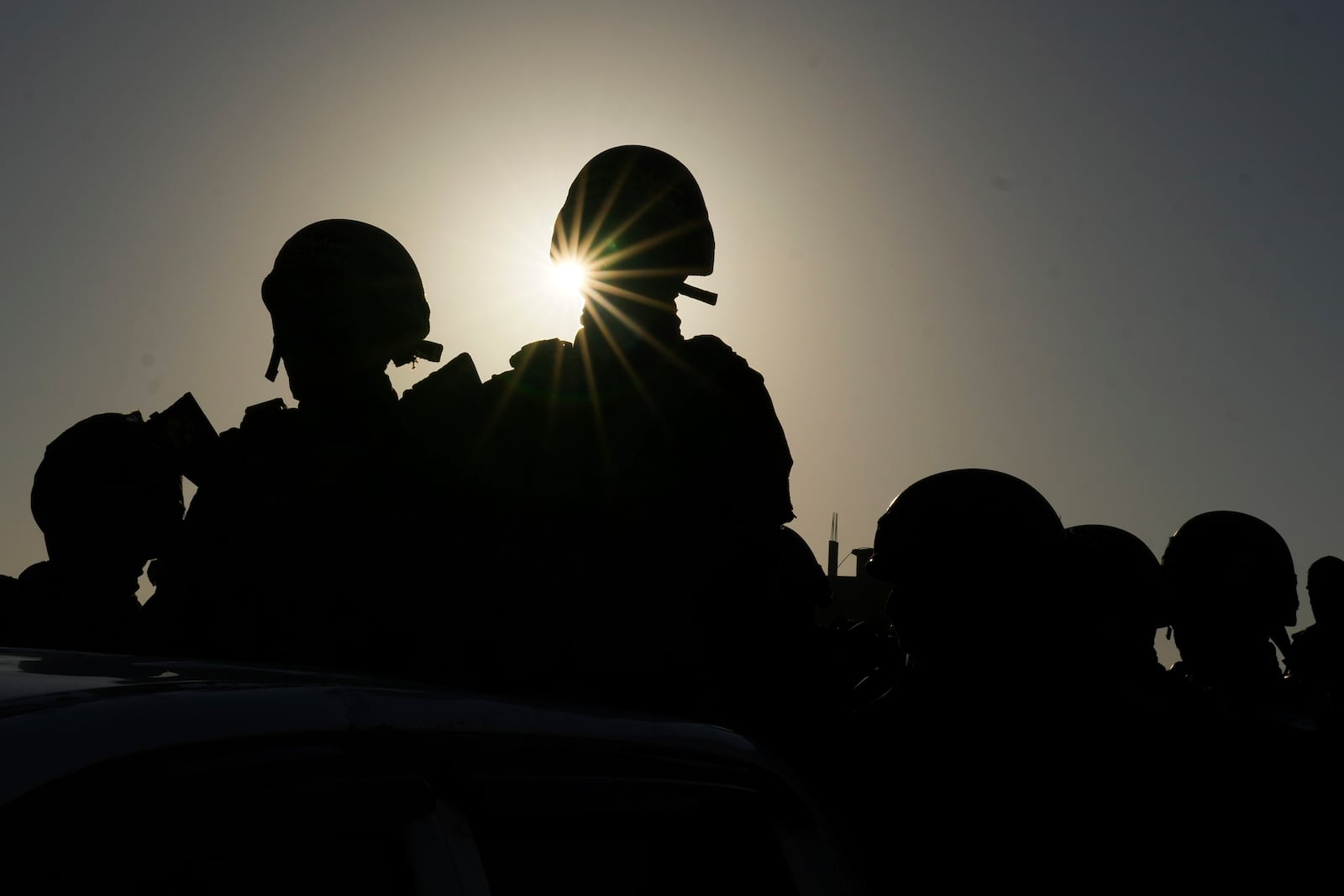 The sun silhouettes Islamic Jihad fighters ahead of a hostages' release in Khan Younis, Gaza Strip, on Saturday, Feb. 15, 2025. (AP Photo/Abdel Kareem Hana)