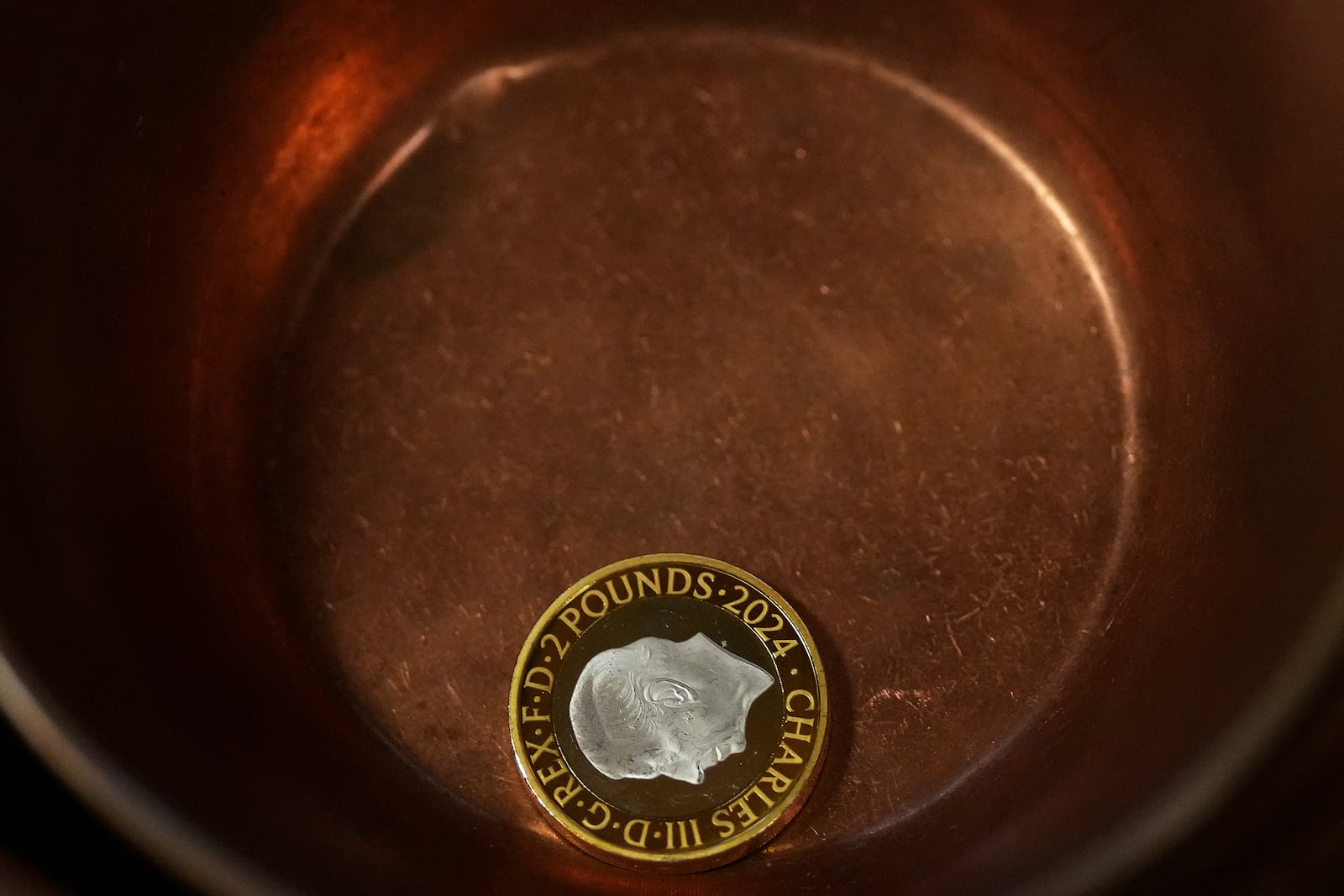 A two Pound gold coin lies in the approved copper bowl during the "Trial of the Pyx,'' a ceremony that dates to the 12th Century in which coins are weighed in order to make certain they are up to standard, at the Goldsmiths' Hall in London, Tuesday, Feb. 11, 2025.(AP Photo/Frank Augstein)