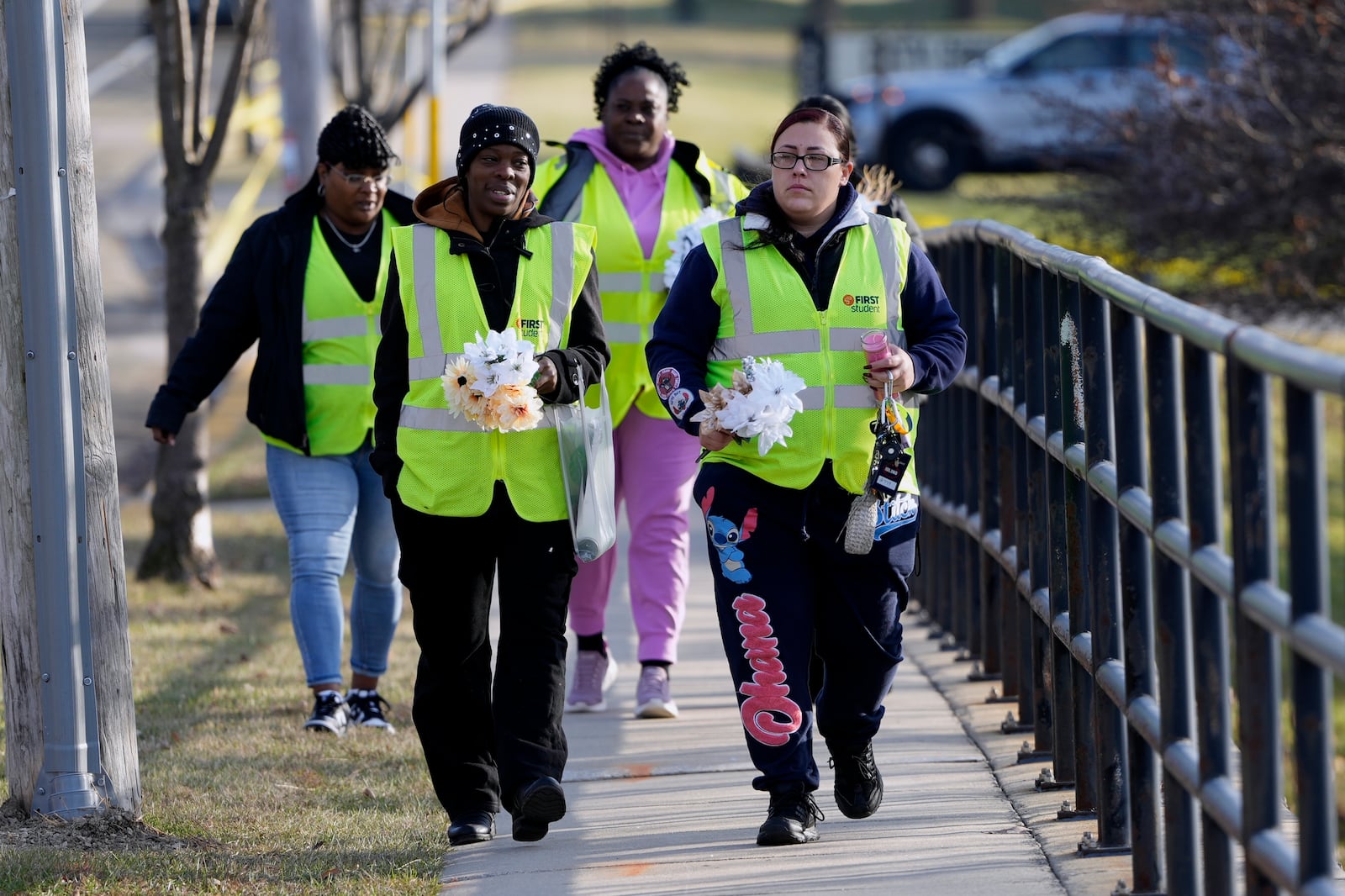 A group makes their way to leave flowers outside the Abundant Life Christian School Tuesday, Dec. 17, 2024 in Madison, Wis., following a shooting on Monday. (AP Photo/Morry Gash)