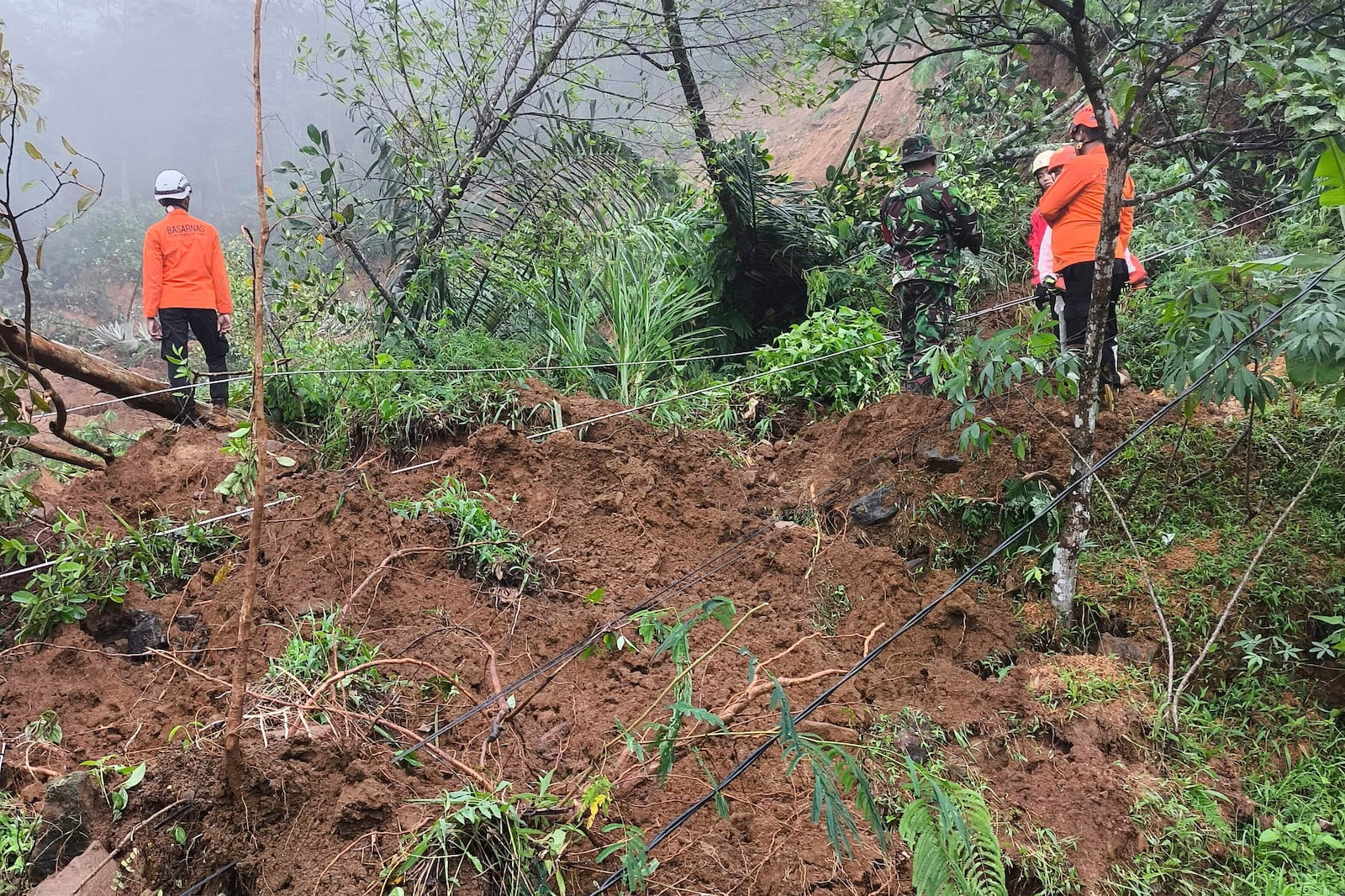 In this undated photo released by Indonesia's National Disaster Management Agency (BNPB) on Wednesday, Jan. 22, 2025, rescuers search for the victims of flash flood which triggered a landslide, in Pekalongan, Central Java, Indonesia. (BNPB via AP)