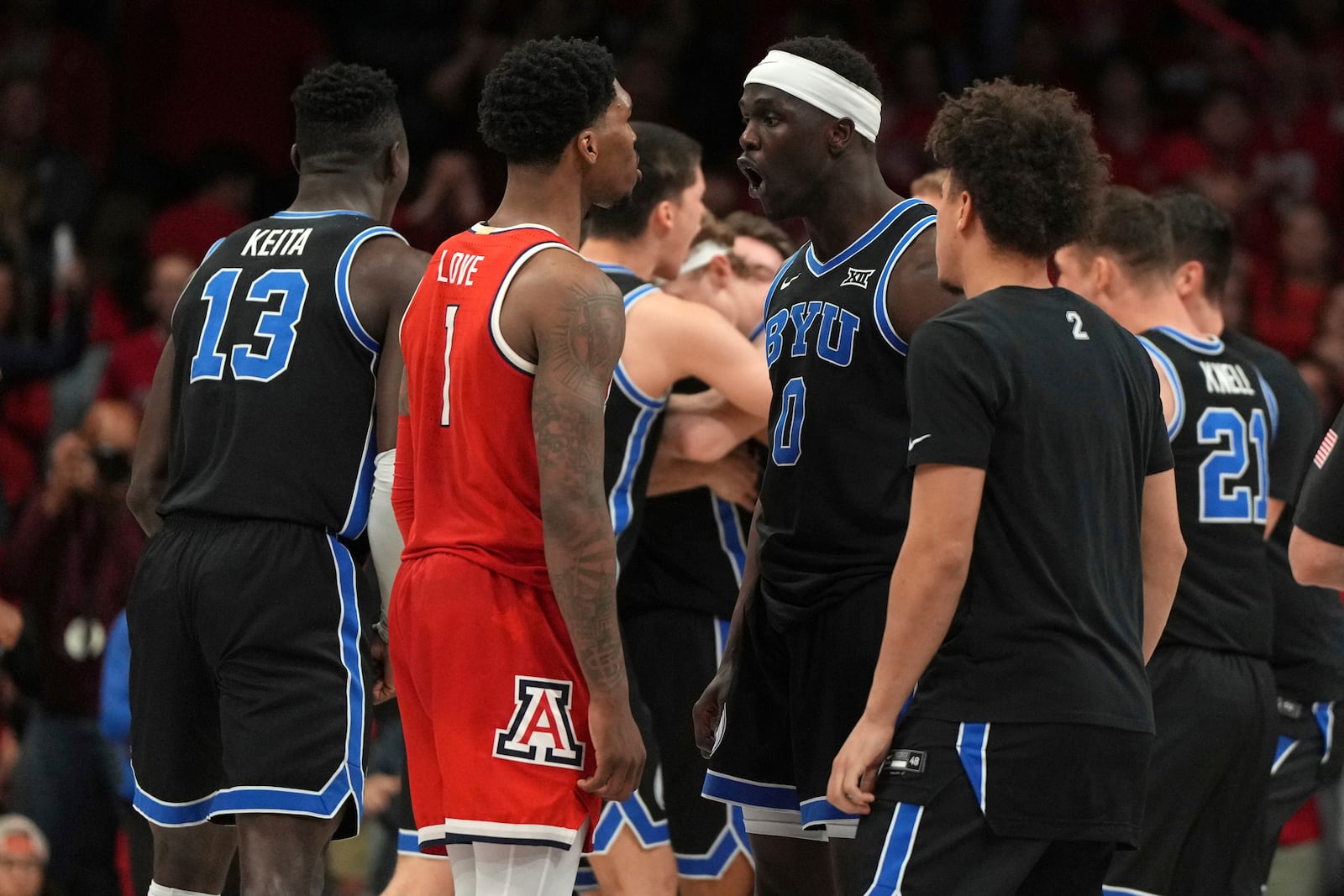 Arizona guard Caleb Love (1) and BYU forward Mawot Mag (0) talk to each other during the second half of an NCAA college basketball game, Saturday, Feb. 22, 2025, in Tucson, Ariz. BYU won 96-95. (AP Photo/Rick Scuteri)