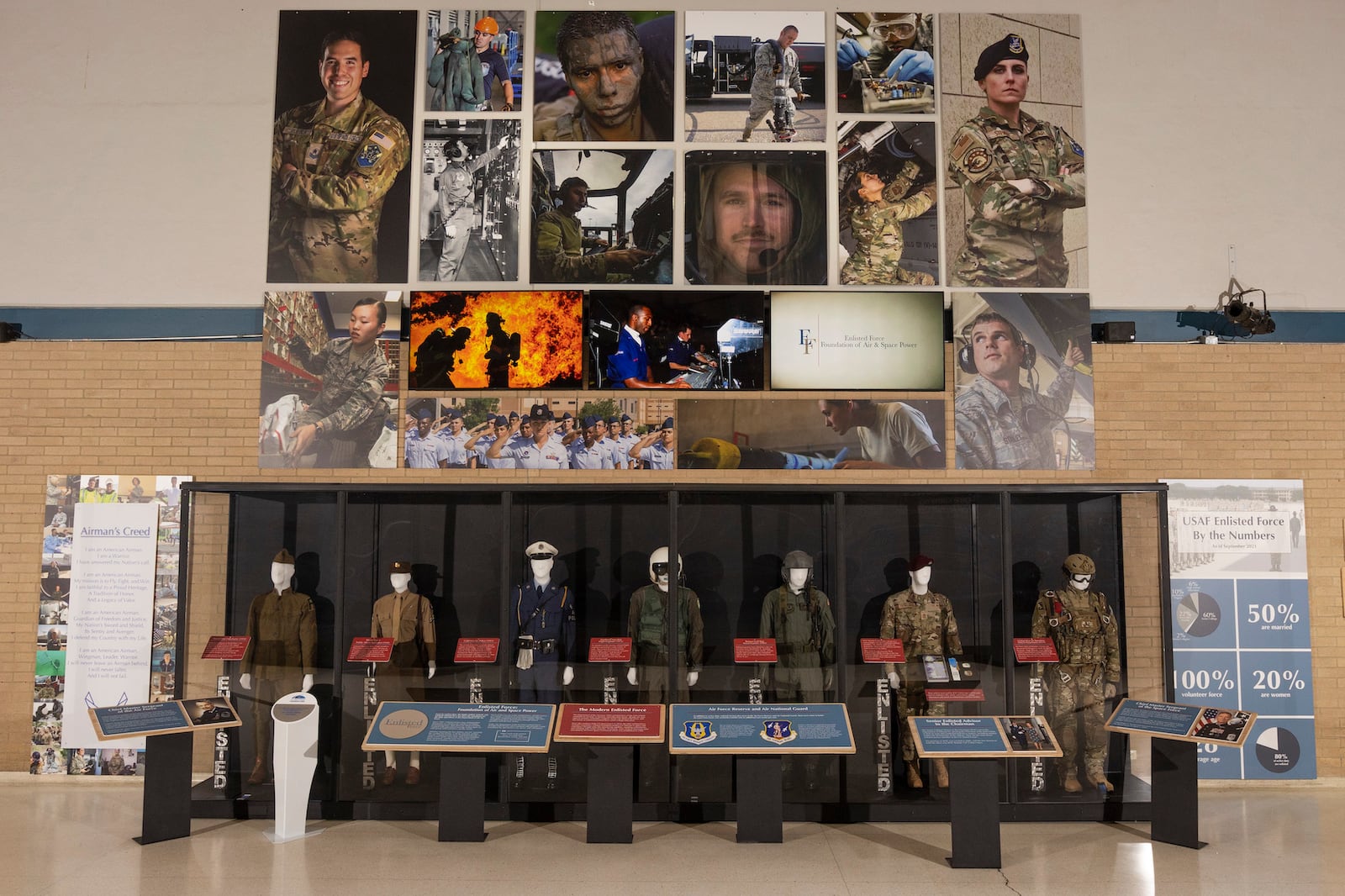 This grand display of the Enlisted Force stands in the National Museum of the U.S. Air Force’s Kettering Hall as a tribute to the backbone of the Air Force. The display shows the roles of Airmen past and present through photographs and video. Six mannequins display uniforms of Airmen from 1918 to 2019 and include a WWI mechanic, WWII Public Affairs Specialist, Cold War Police Officer, Southeast Asia War Flight Engineer, Persian Gulf War Aerial Gunner and Global War on Terrorism HALO Parachutist. 
The full exhibit, which contains nearly fifty elements, is placed throughout the ten galleries of the museum.
Since 1907, enlisted Airmen have distinguished themselves as a technically minded and highly professional force. Their thirst for advanced skills, coupled with specialized training, makes them an elite group which produces quality results.
Whether repairing the first military aircraft, reporting the weather for D-Day, or flying remotely piloted aircraft, enlisted Airmen have contributed greatly in many career fields. Over time, their responsibilities have increased, and the force has become more diversified in abilities and characteristics.
(U.S. Air Force photo by Ty Greenlees)