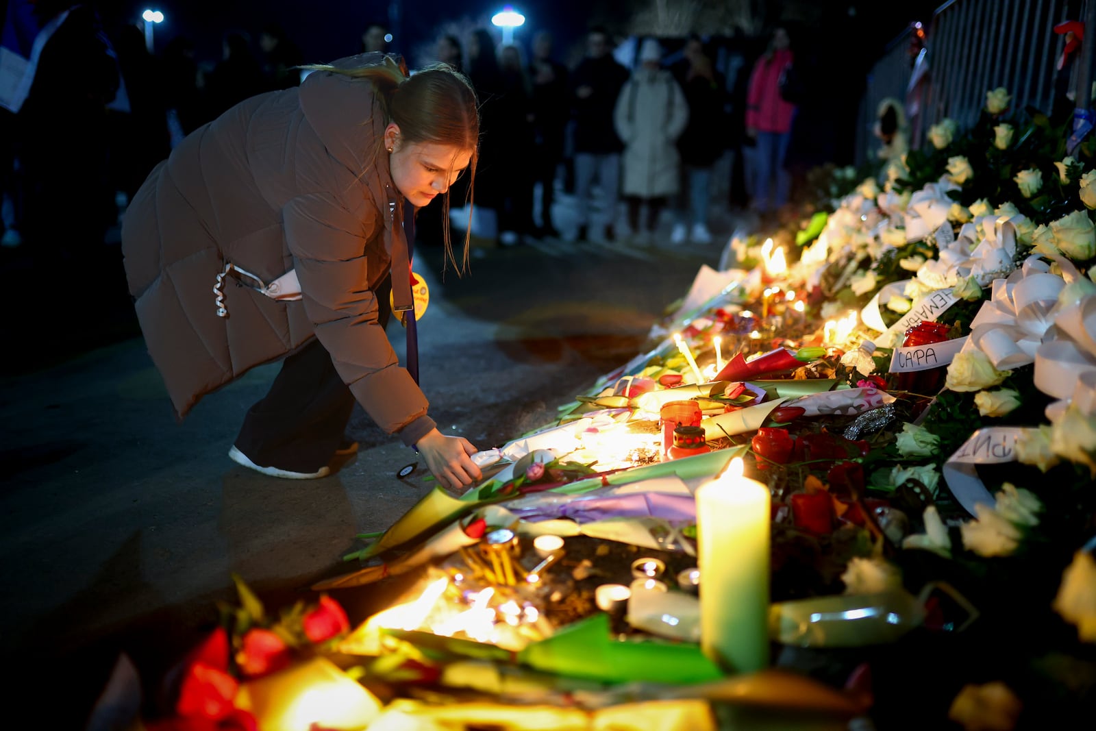 A a woman places flowers at the site of the collapse of a concrete canopy that killed 15 people more than two months ago, during a protest in Novi Sad, Serbia, Friday, Jan. 31, 2025. (AP Photo/Armin Durgut)