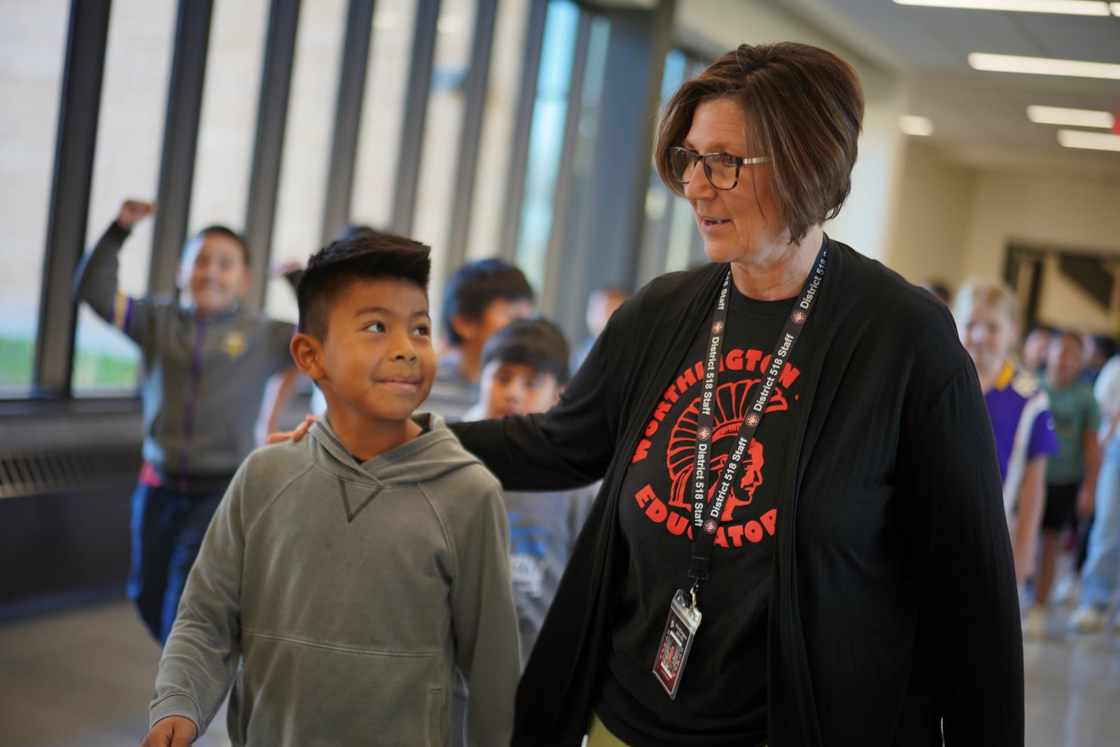 Suzy Brandner, right, who has taught in Worthington for 34 years, talks with a student walking down the hall at the intermediate school, which serves grades three through five, in Worthington, Minn., on Tuesday, Oct. 22, 2024. (AP Photo/Jessie Wardarski)