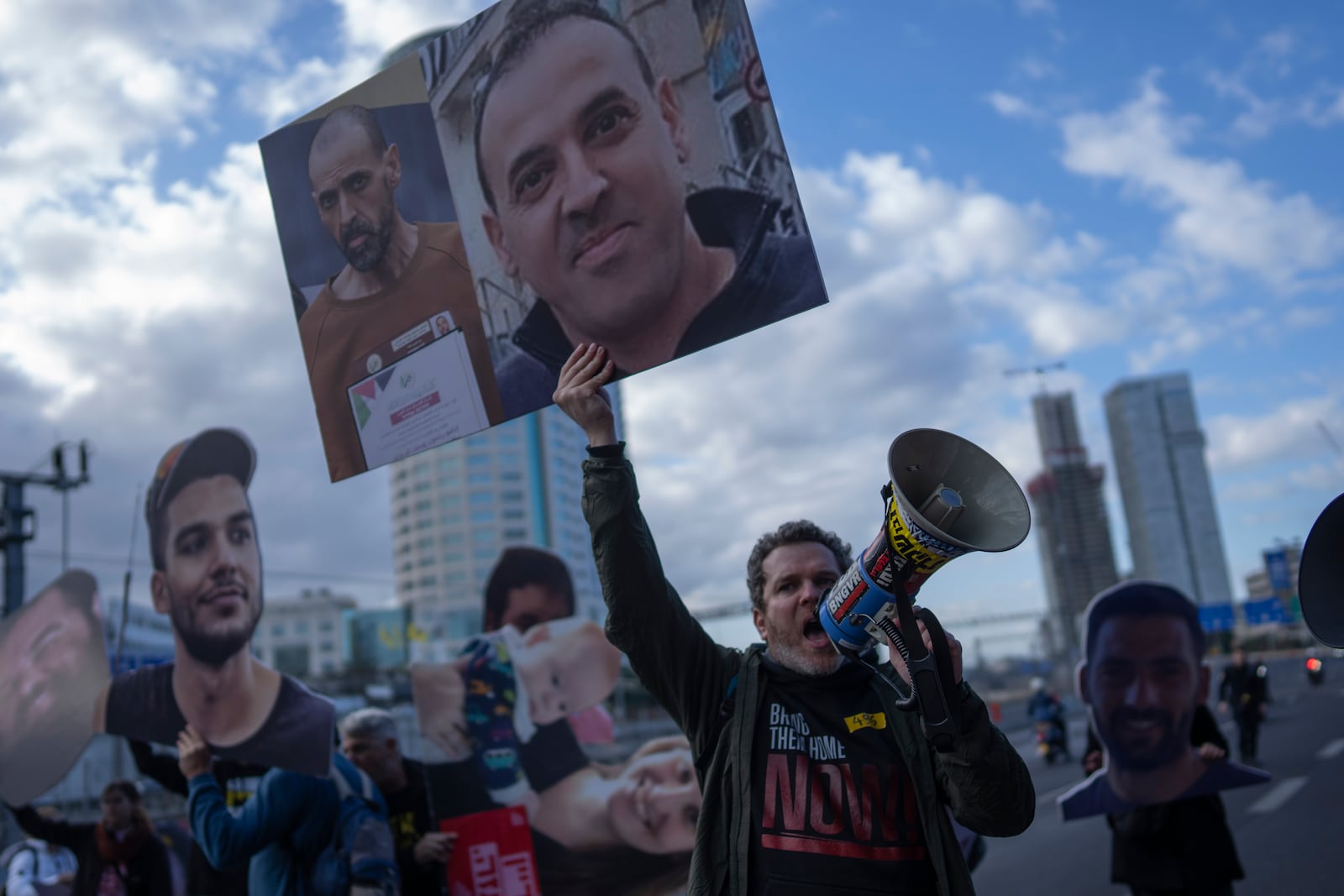 A demonstrator holding photos of freed Israeli hostage Eli Sharabi before and after his captivity blocks a highway during a protest demanding all hostages release from Hamas captivity, in Tel Aviv, Israel, Thursday, Feb. 13, 2025. (AP Photo/Oded Balilty)