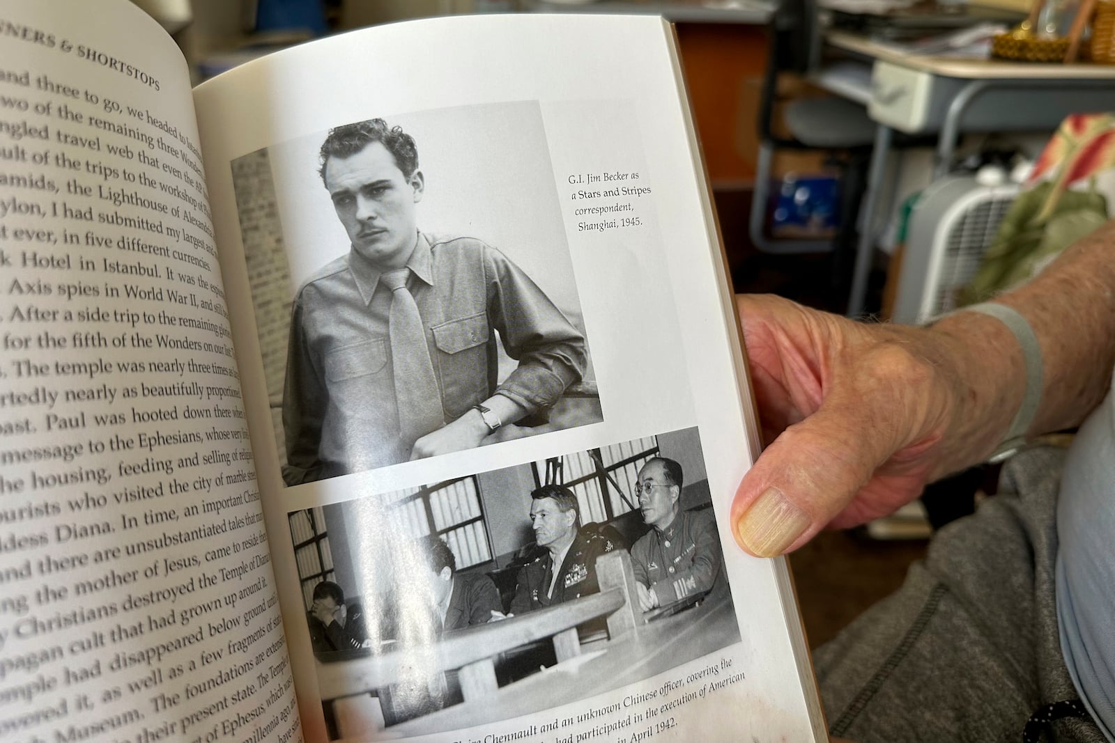 Jim Becker, a former Associated Press journalist, holds a book showing a 1945 photo of him as a Stars and Stripes correspondent in Shanghai, at his home in Kaneohe, Hawaii, May 21, 2024. (AP Photo/Audrey McAvoy)