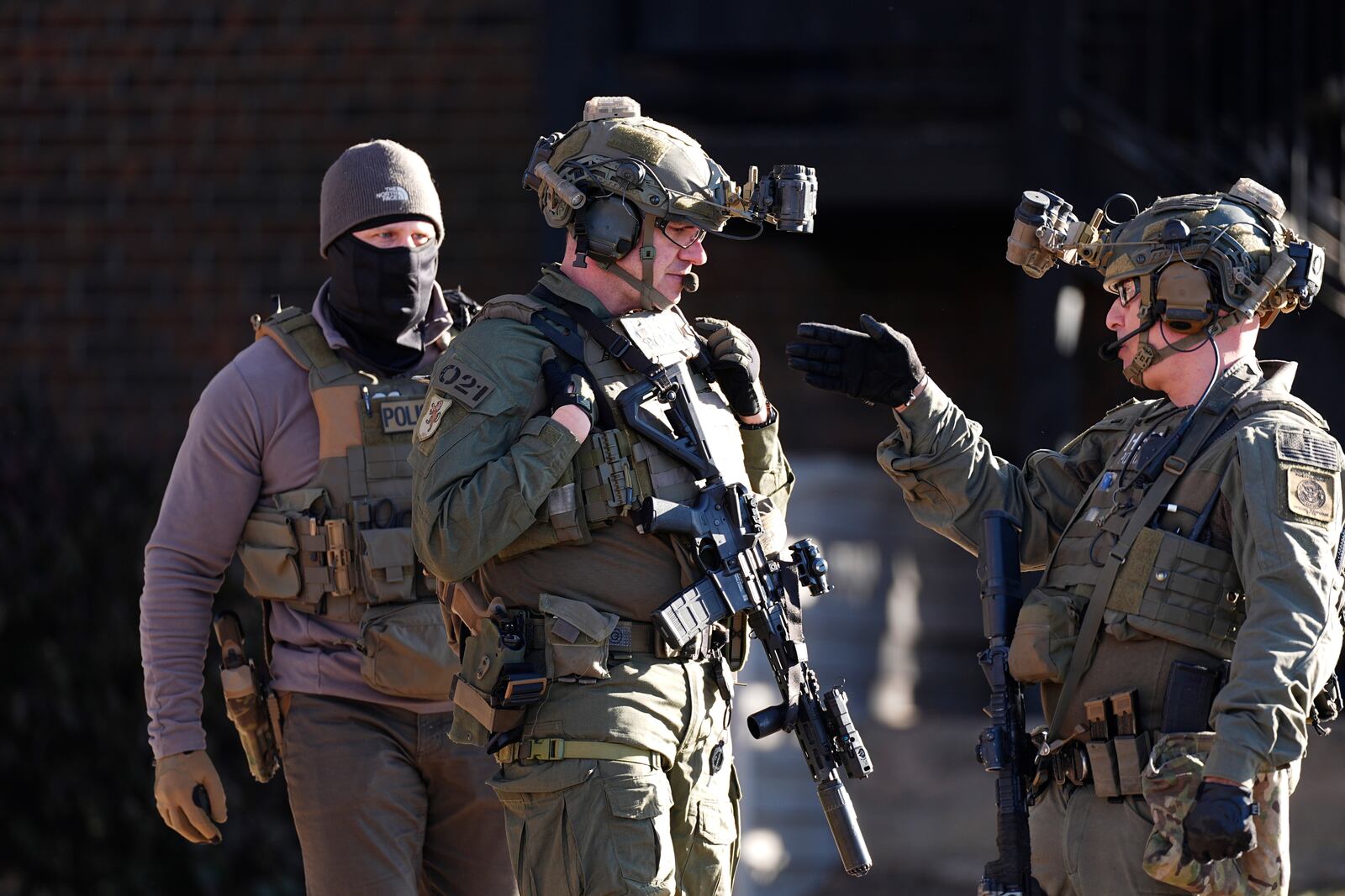 Law officials confer during a raid Wednesday, Feb. 5, 2025, in east Denver. (AP Photo/David Zalubowski)