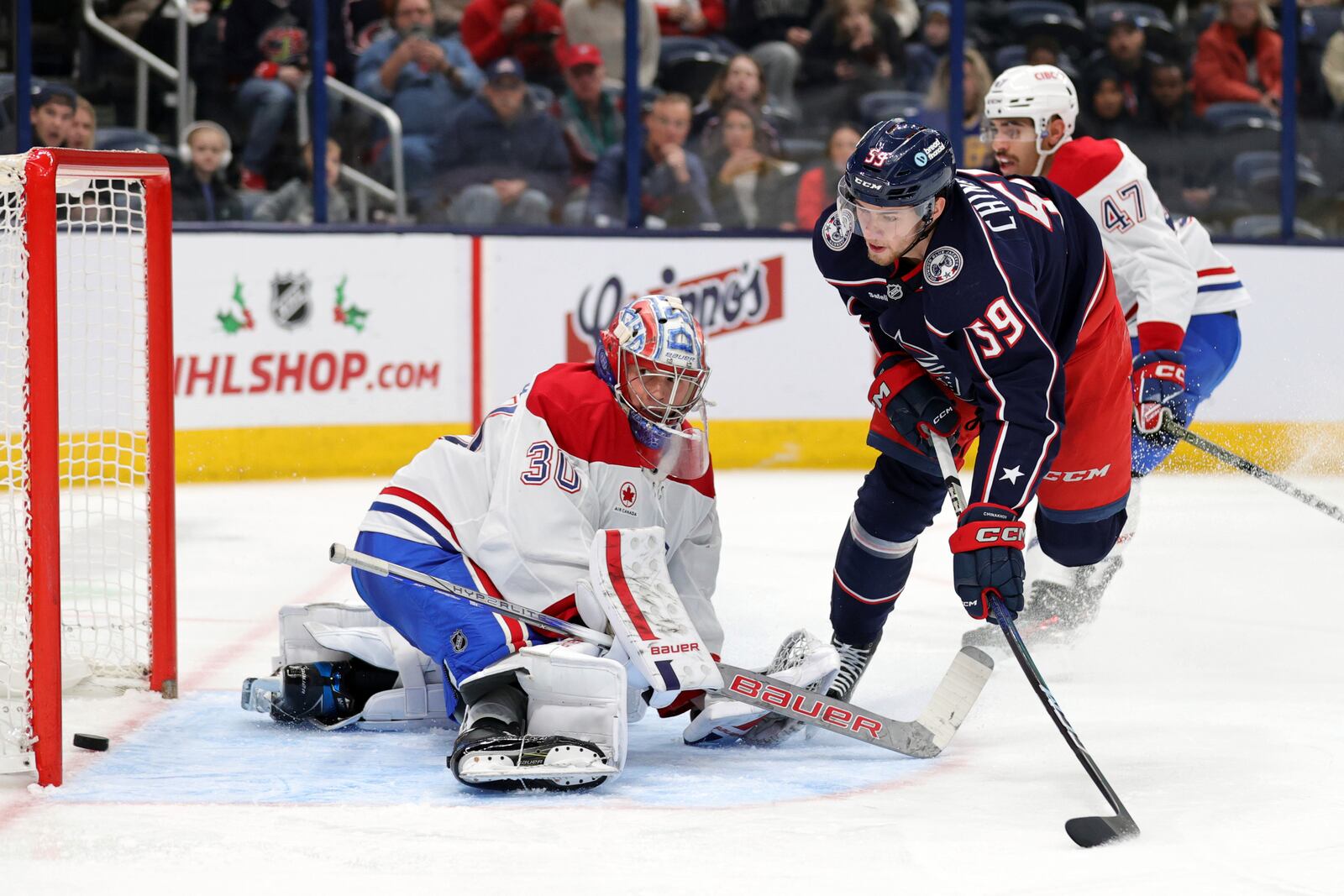 Columbus Blue Jackets forward Yegor Chinakhov, center, scores past Montreal Canadiens goalie Cayden Primeau, left, in front of Canadiens defenseman Jayden Struble during the second period of an NHL hockey game in Columbus, Ohio, Wednesday, Nov. 27, 2024. (AP Photo/Paul Vernon)