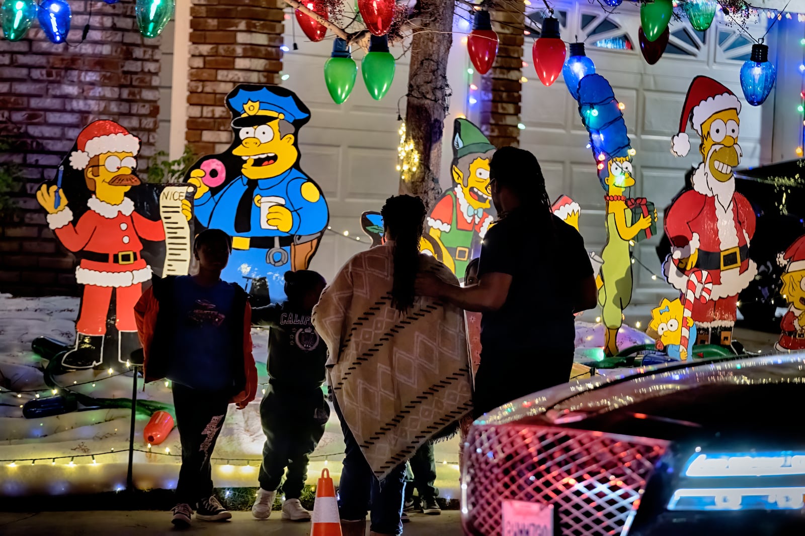 The Simpsons cartoon characters decorate the front of a Wakefield Winter Wonderland as local residents walk the neighborhood decorated with Christmas lights in Santa Clarita, Calif. on Dec. 17, 2024. (AP Photo/Richard Vogel)