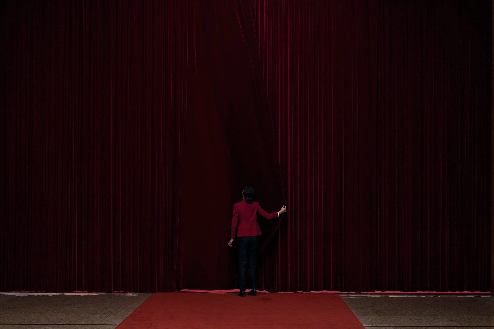 A hostess closes a curtain after delegates attending the opening session of the Chinese People's Political Consultative Conference at the Great Hall of the People in Beijing, Tuesday, March 4, 2025. (AP Photo/Andy Wong)