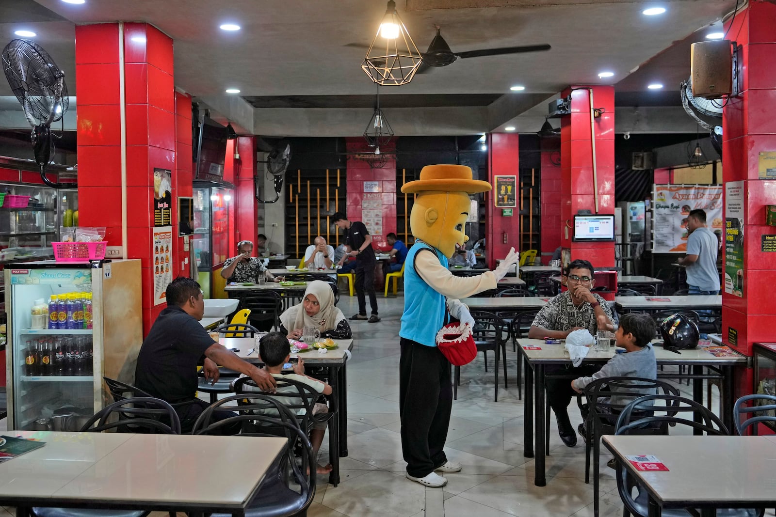 A street busker gestures as he talks to a guests at a coffee shop in Banda Aceh, Indonesia, Friday, Dec. 13, 2024. (AP Photo/Achmad Ibrahim)