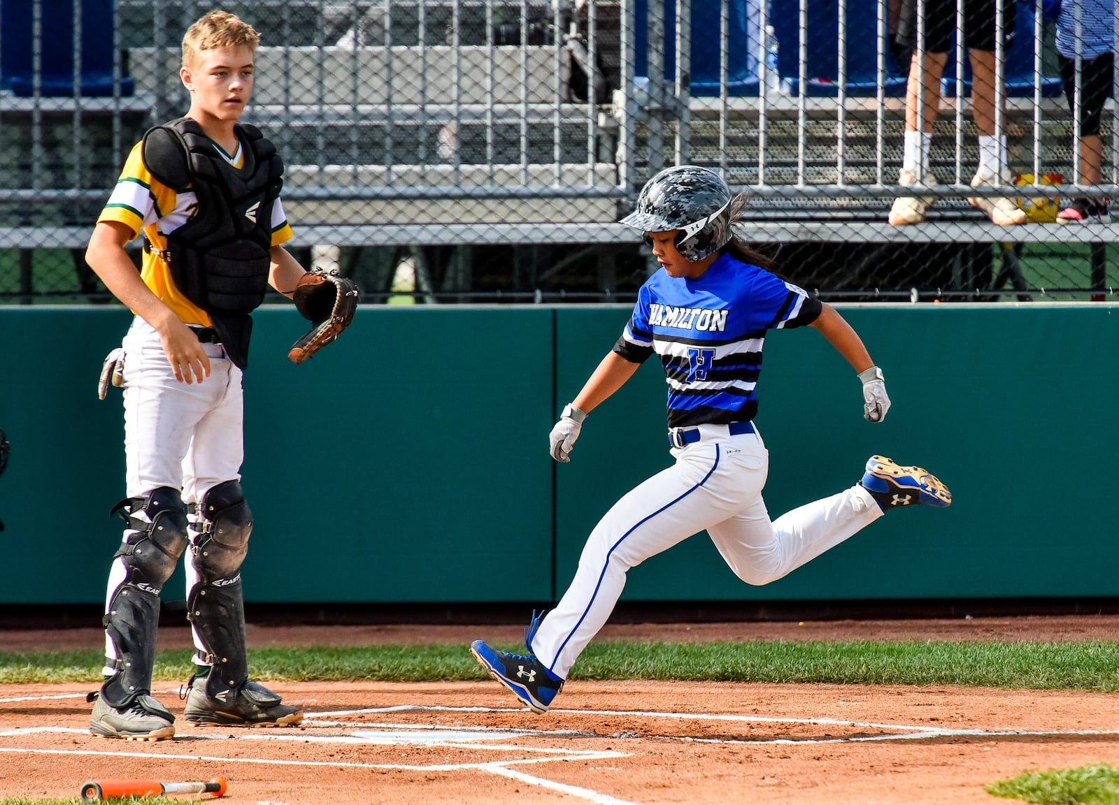 Hamilton West Side’s Katelyn Polido scores the first run of the game in front of Grosse Pointe Woods-Shores (Mich.) catcher Ryan Jones on Monday during a 10-2 triumph in the Little League Great Lakes Regional at Grand Park Sports Campus in Westfield, Ind. NICK GRAHAM/STAFF