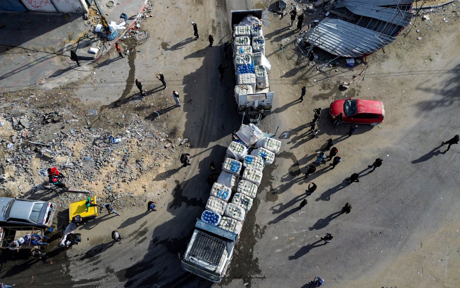 A drone photo shows humanitarian aid trucks enter through the Kerem Shalom crossing from Egypt into the Gaza Strip, as a ceasefire deal between Israel and Hamas went into effect, Sunday, Jan. 19, 2025. (AP Photo/Jehad Alshrafi)