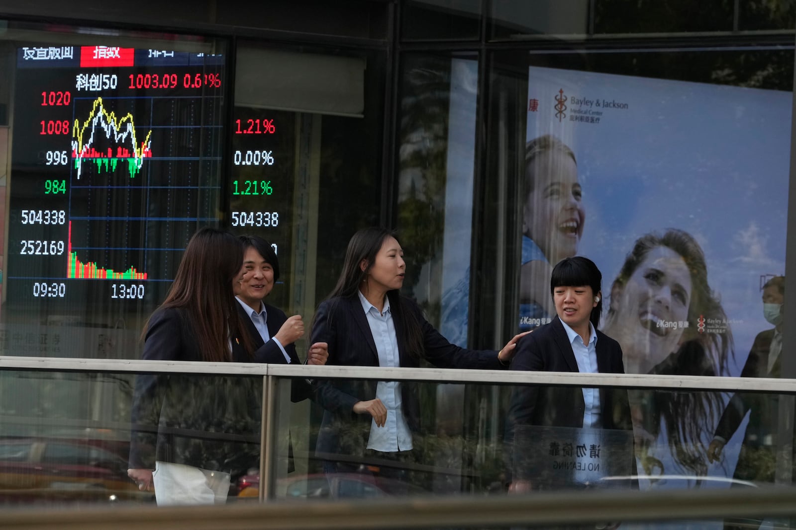 Women pass by a display board showing Chinese stock market movements on the U.S. presidential election day, in Beijing, Wednesday, Nov. 6, 2024. (AP Photo/Ng Han Guan)