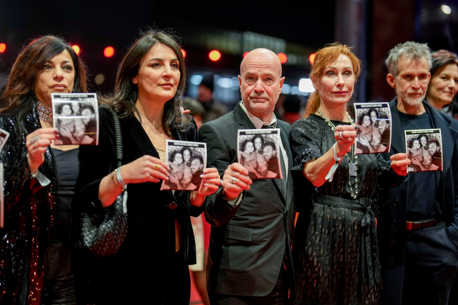 German actors and actresses hold photos of Israeli hostage David Cunio upon arrival at the opening of the International Film Festival, Berlinale, in Berlin, Thursday, Feb. 13, 2025. (AP Photo/Markus Schreiber)