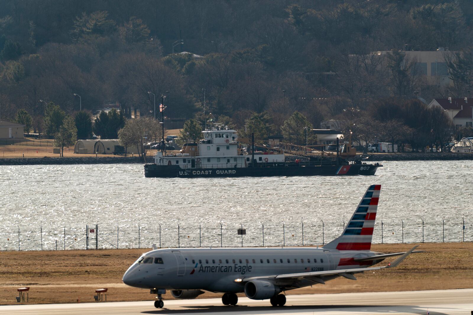 An American airline aircraft take off as coast guard boat is seen around a wreckage site in the Potomac River from Ronald Reagan Washington National Airport, Saturday, Feb. 1, 2025, in Arlington, Va. (AP Photo/Jose Luis Magana)