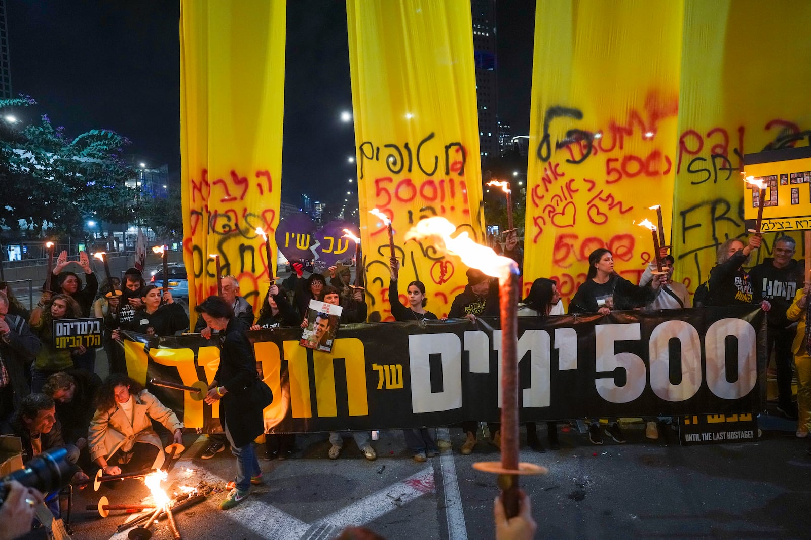 Relatives and supporters of Israelis held hostage by Hamas in Gaza light torches during a rally marking 500 days of captivity and demanding their release in Tel Aviv, Israel, on Monday, Feb. 17, 2025. (AP Photo/Ariel Schalit)