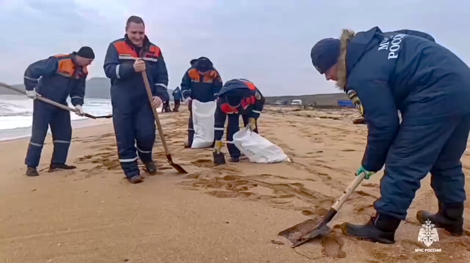 In this photo taken from video released by Russian Emergency Ministry Press Service on Saturday, Jan. 4, 2025, rescuers work to clean up tons of fuel oil that spilled out of two storm-stricken tankers more than two weeks ago in the Kerch Strait, in Russia's southern Krasnodar region. (Russian Emergency Ministry Press Service via AP)