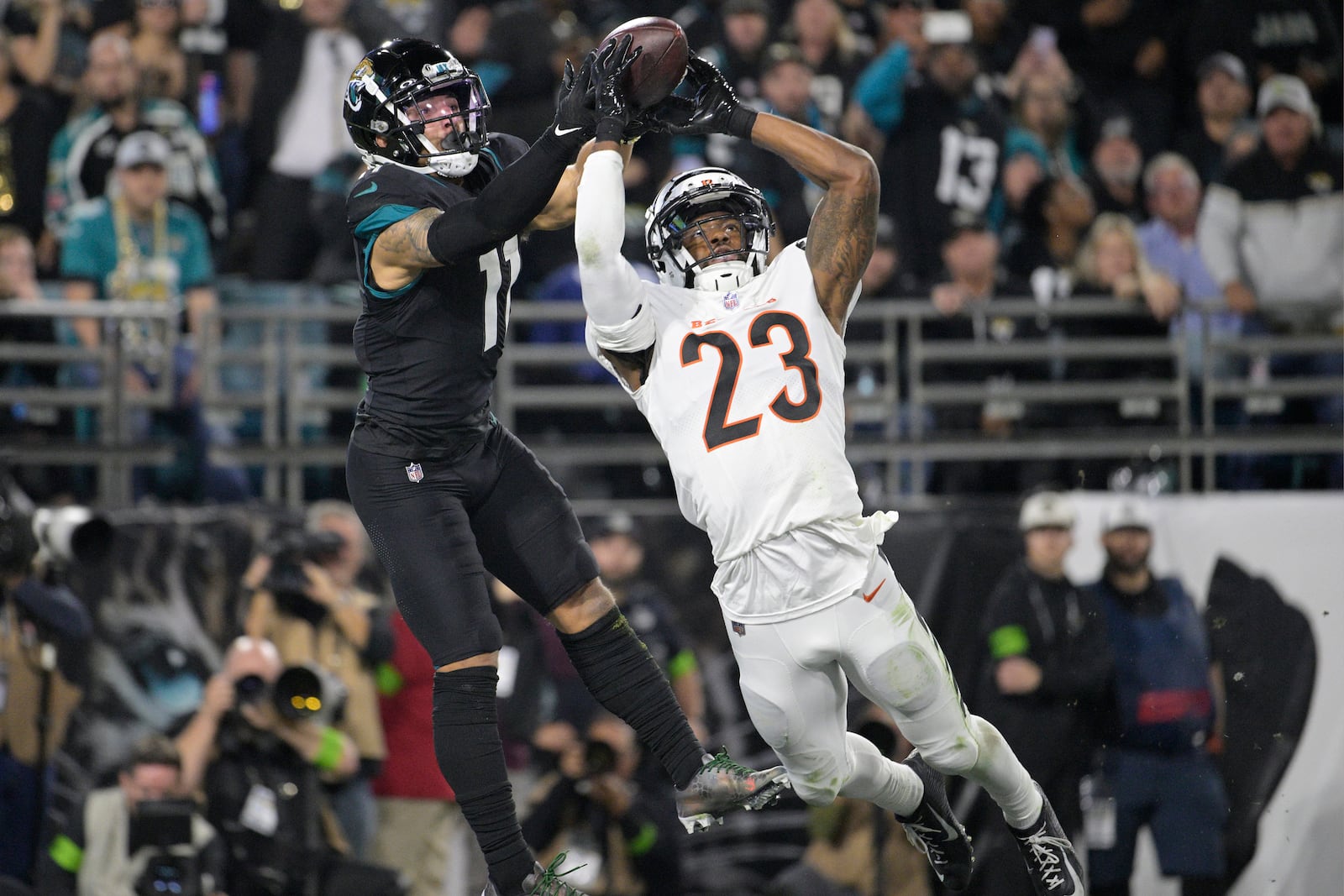 Jacksonville Jaguars wide receiver Parker Washington (11) grabs a pass in the end zone for a touchdown as Cincinnati Bengals safety Dax Hill (23) defends, during the first half of an NFL football game, Monday, Dec. 4, 2023, in Jacksonville, Fla. (AP Photo/Phelan M. Ebenhack)