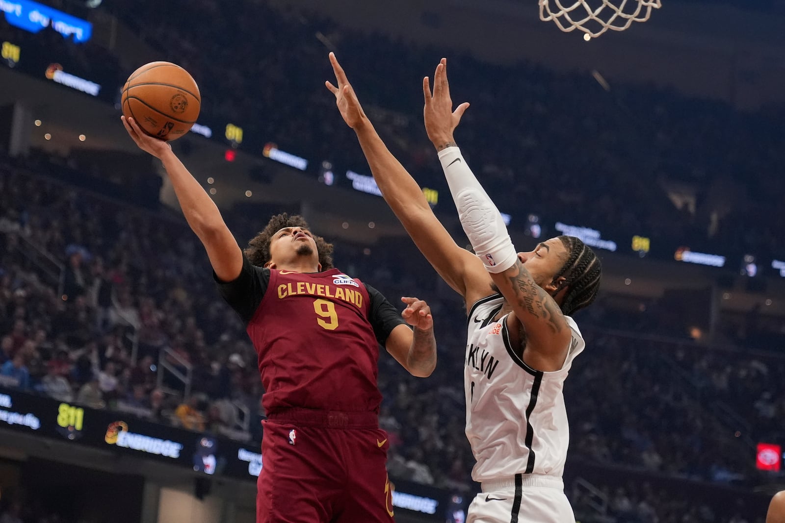 Cleveland Cavaliers guard Craig Porter Jr. (9) shoots as Brooklyn Nets' Trenton Watgford, right, defends in the first half of an NBA basketball game Tuesday, March 11, 2025, in Cleveland. (AP Photo/Sue Ogrocki)