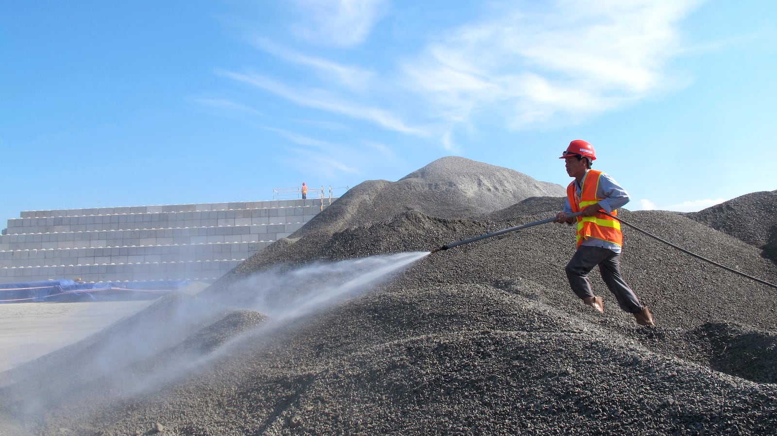 FILE- A Vietnamese worker sprays water over stones to be used in the construction of a silo for storing soil contaminated with Agent Orange dioxide at the site of a former American airbase in Danang, Vietnam on April 24, 2013. (AP Photo/Hau Dinh)