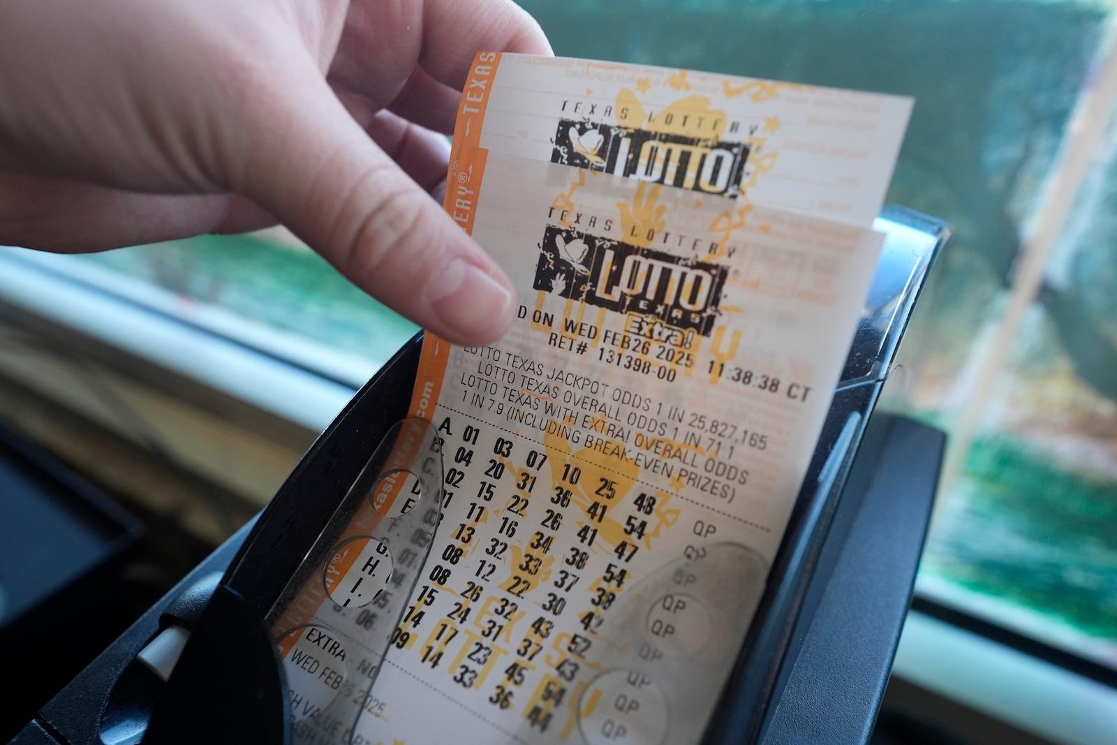 Edith Patlan grabs printed tickets from a Texas Lottery sales terminal at Fuel City in Dallas, Wednesday, Feb. 26, 2025. (AP Photo/LM Otero)