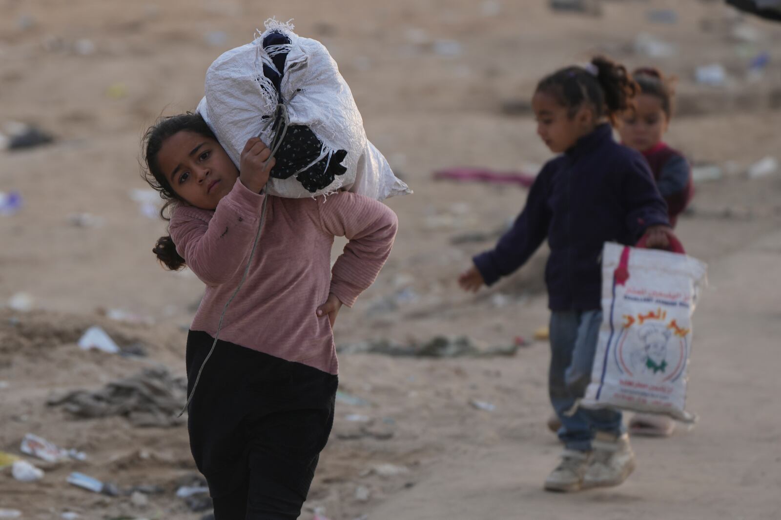 Displaced Palestinians children walk on a road to return to their homes in the northern Gaza Strip, Tuesday, Jan. 28, 2025. (AP Photo/Abdel Kareem Hana)