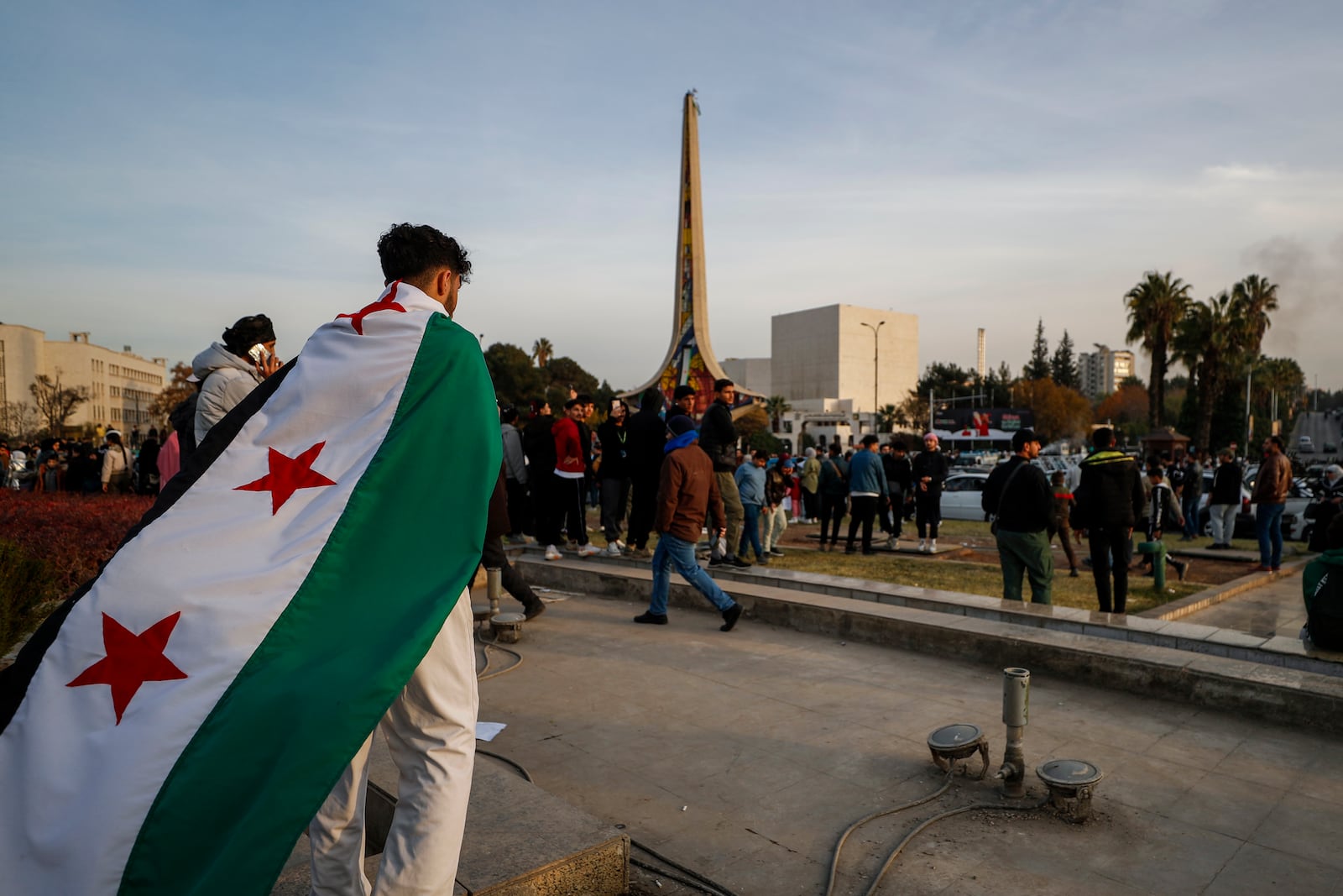 A man holds the revolutionary flag as others celebrating during the third day of the take over of the city by the insurgents in Damascus, Syria, Tuesday, Dec. 10, 2024. (AP Photo/Omar Sanadiki)